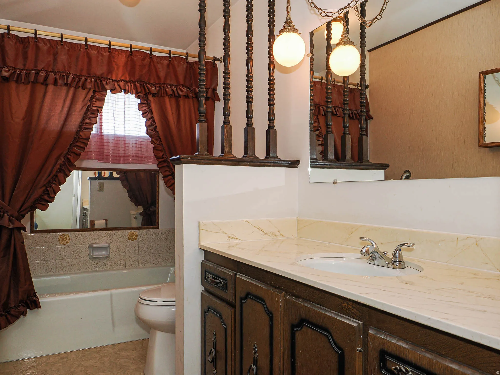 Bathroom featuring a built-in vanity with a stone-finish countertop, an integrated sink, and an ornate dark wood cabinet