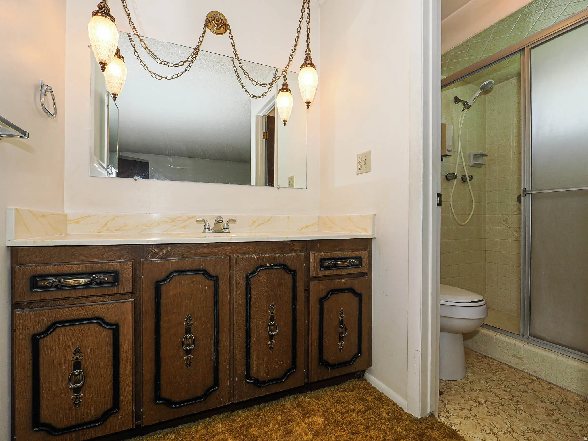 Bathroom vanity featuring a wood-finish cabinet with decorative panels, a light-toned countertop, and a wall-mounted mirror