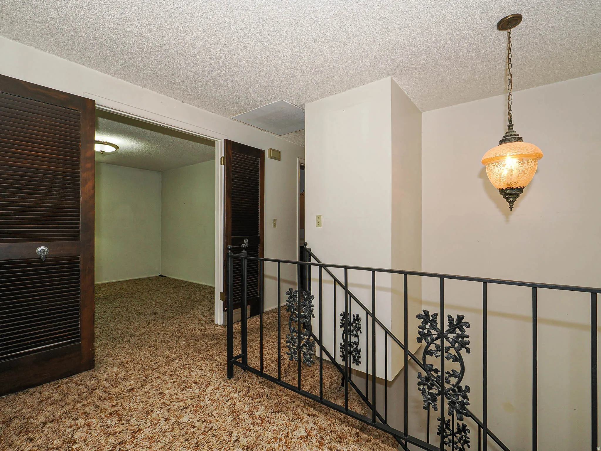 Stairwell featuring an ornate wrought iron railing and a decorative hanging light fixture