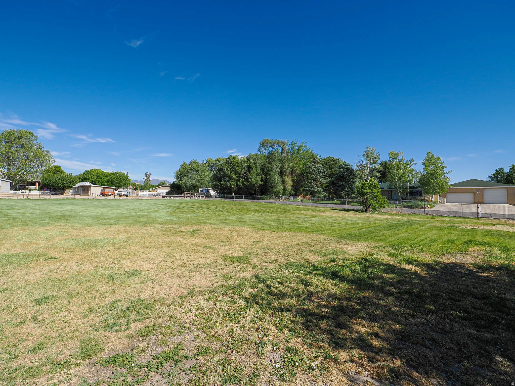 Expansive open field with partial fencing and distant outbuildings