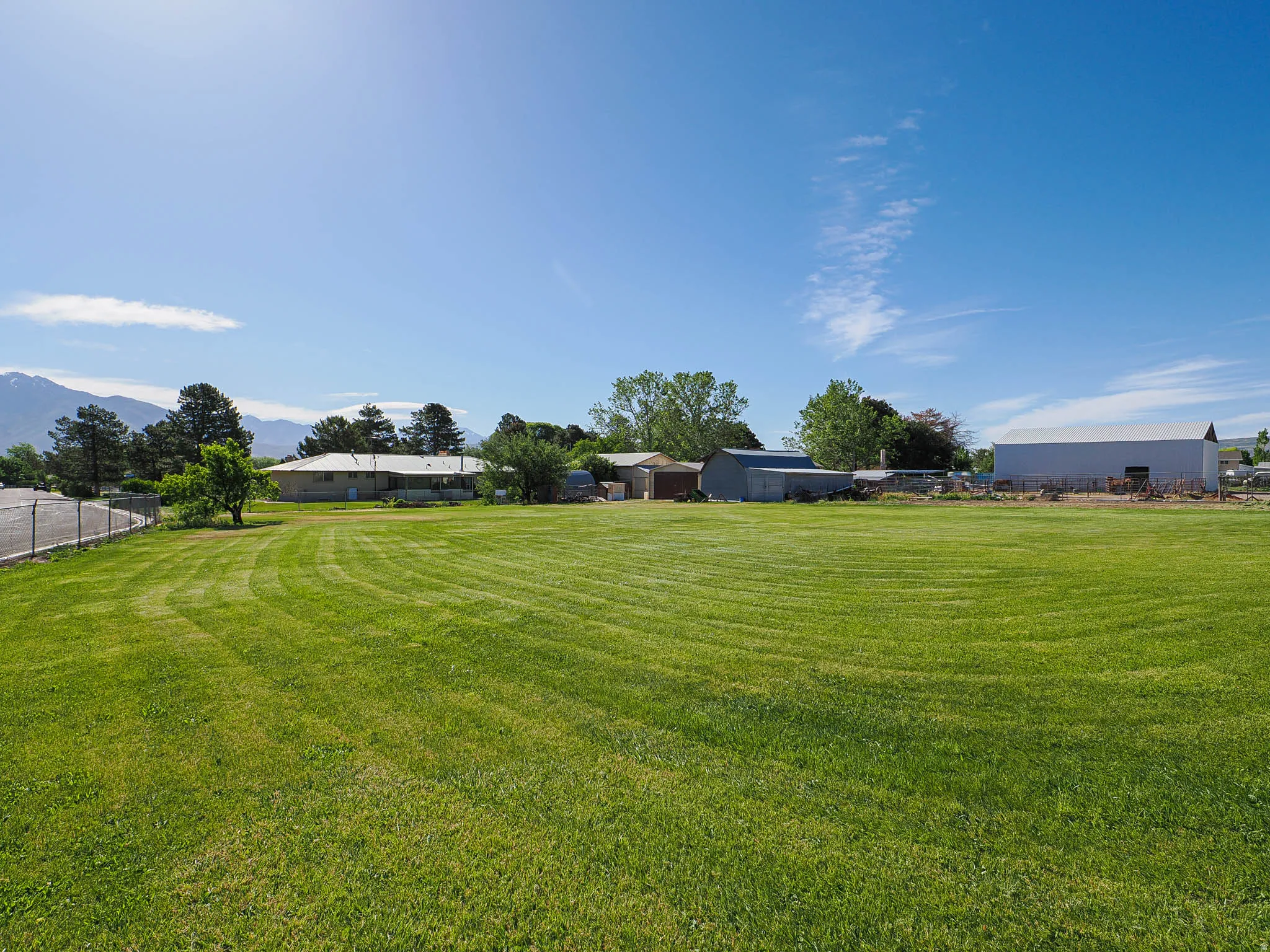 Expansive grassy area featuring a perimeter fence and distant mountainous terrain