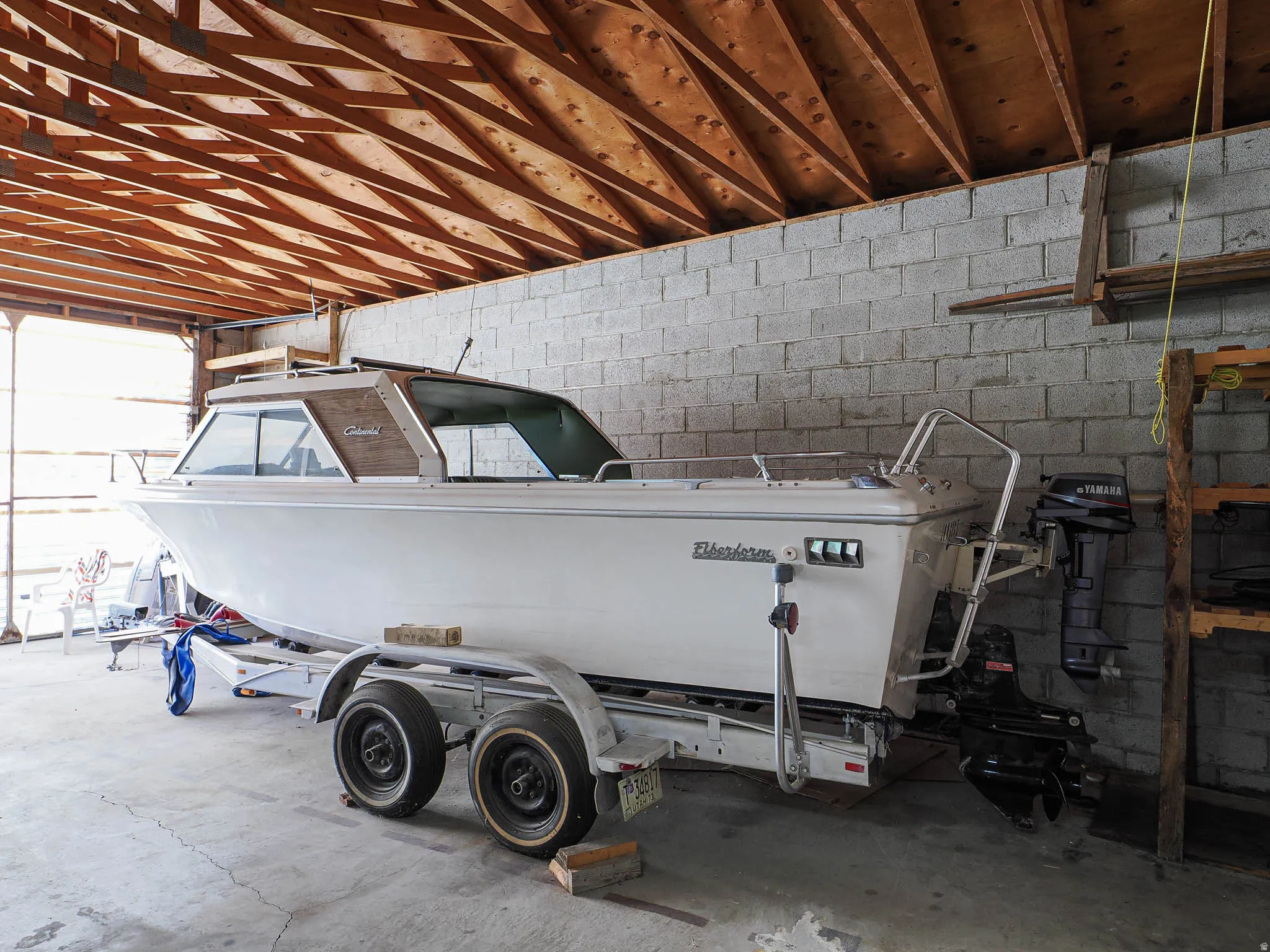 Open storage structure featuring exposed wood rafter ceiling and a concrete block wall