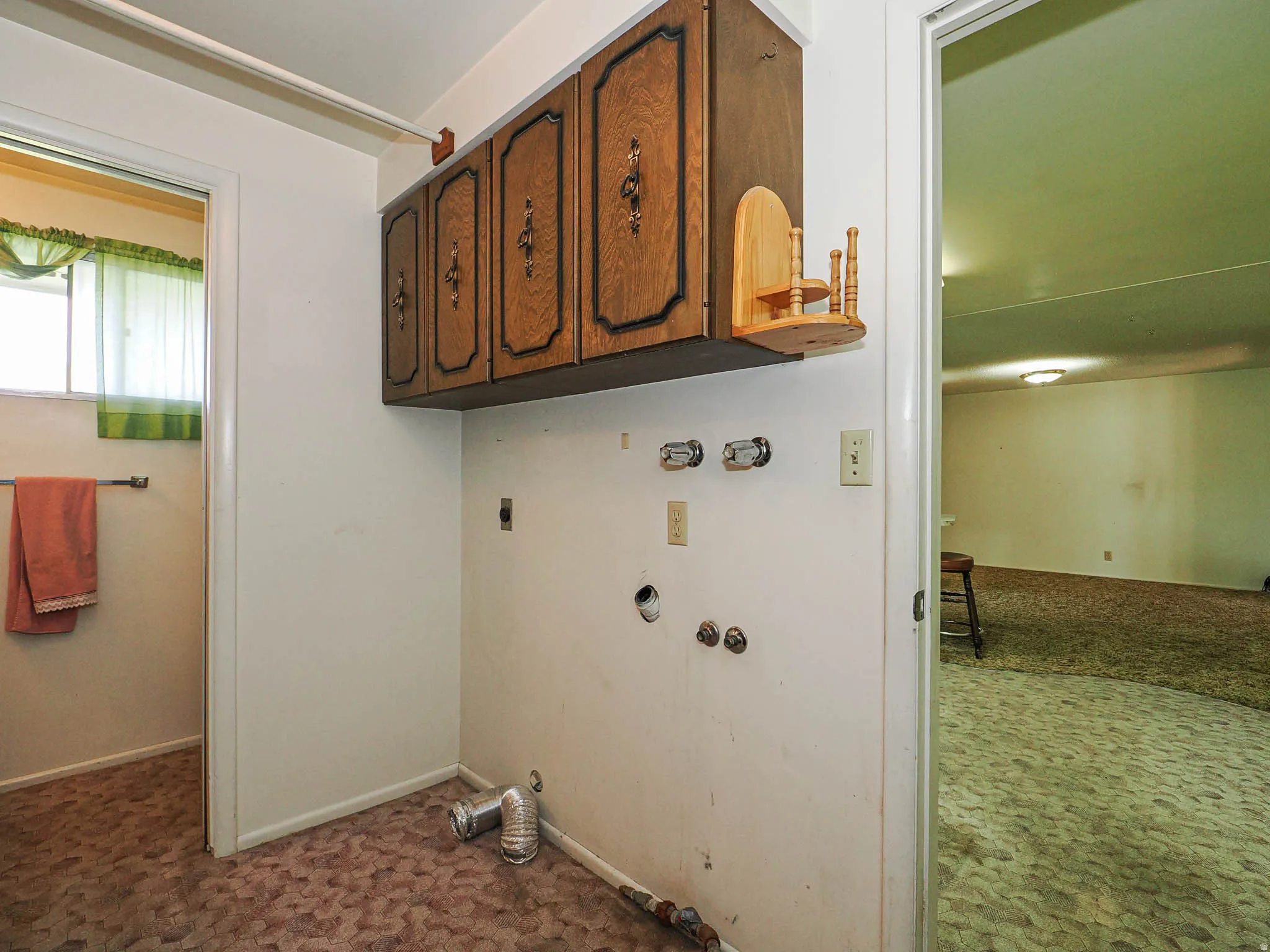Laundry area featuring wood upper cabinetry, utility hookups, and patterned carpet flooring