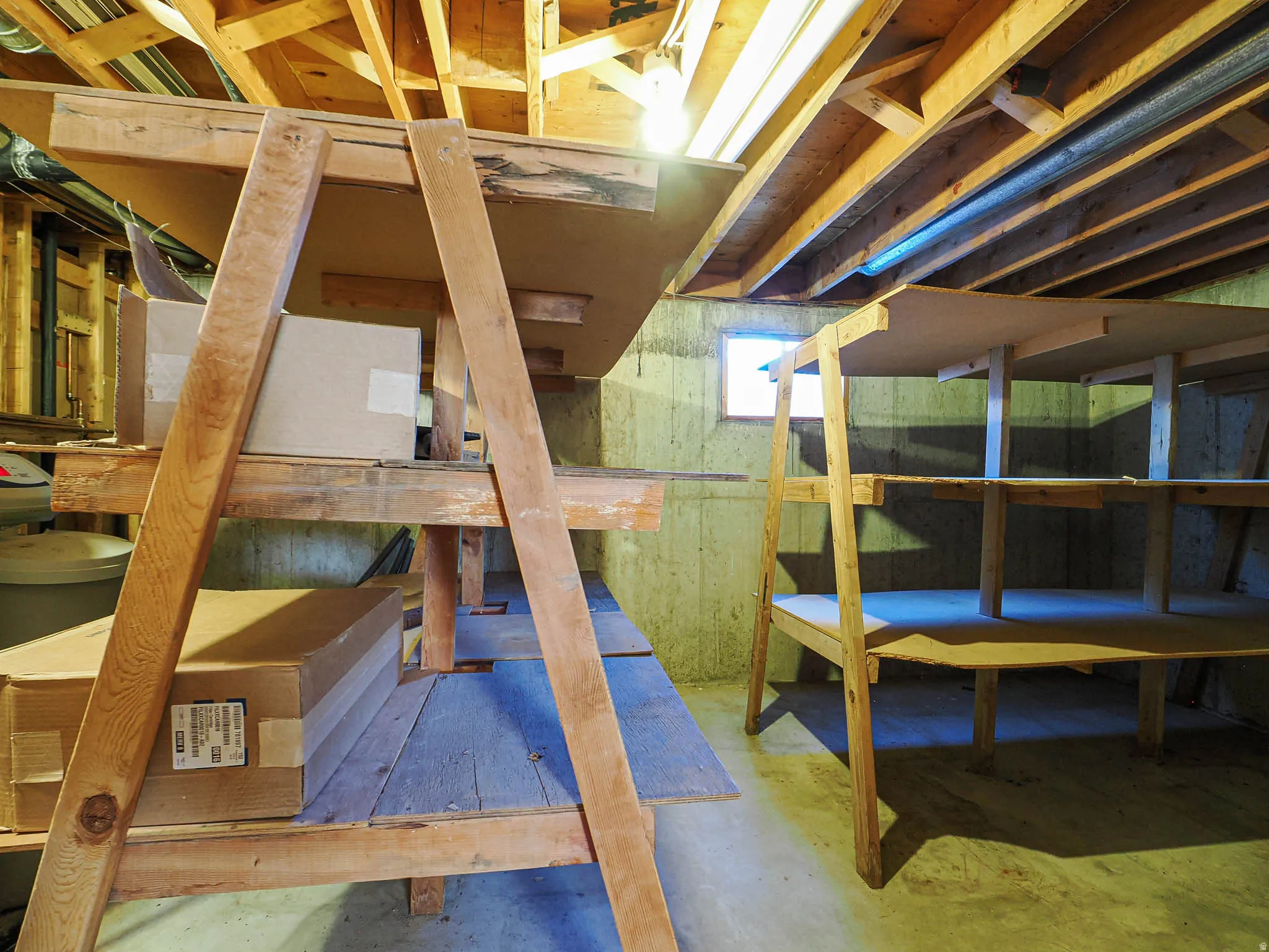 Basement storage area featuring exposed wood joists and concrete walls