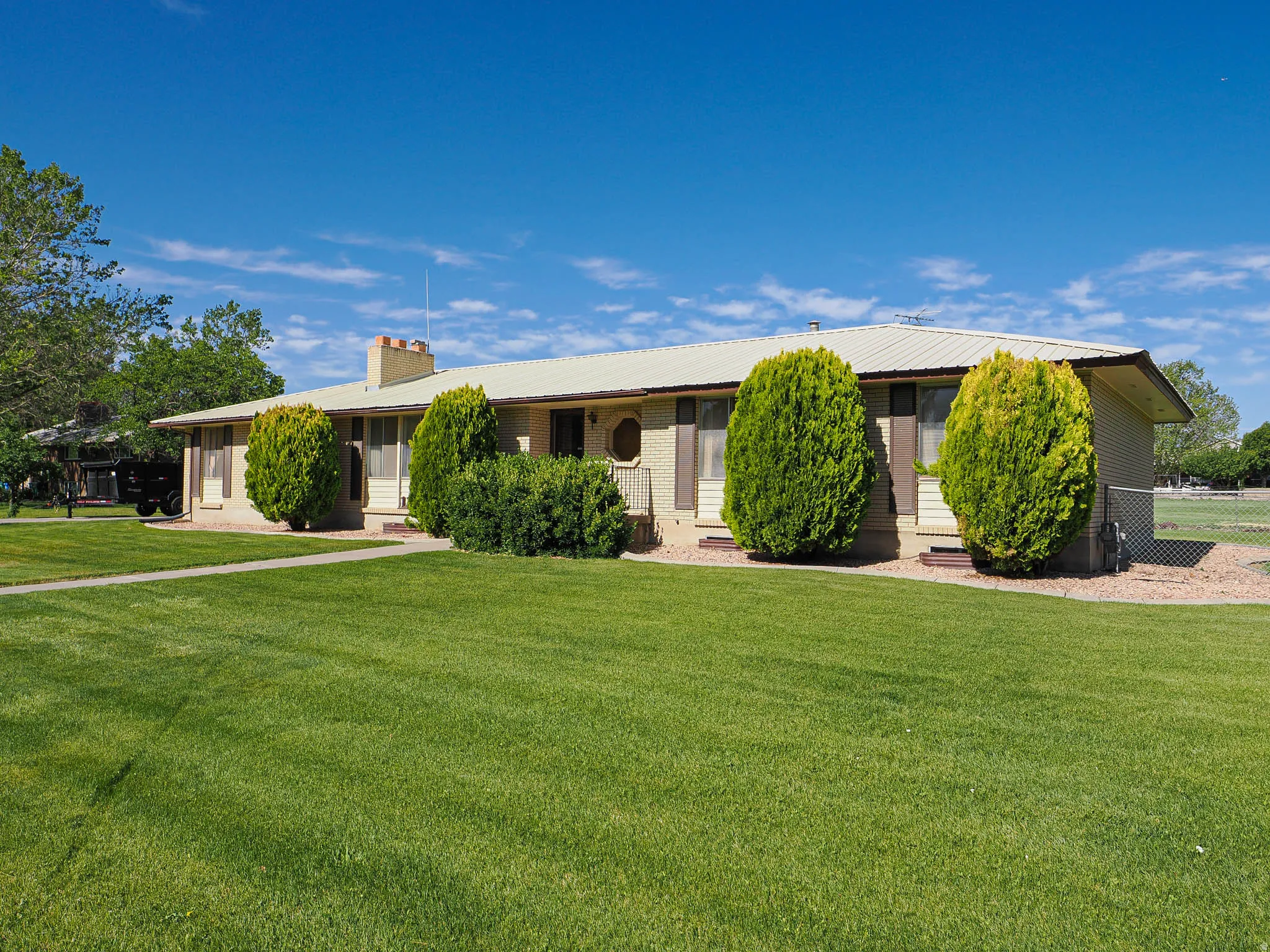 Single-story residence featuring a light-colored stucco exterior, a metal roof, and a prominent chimney