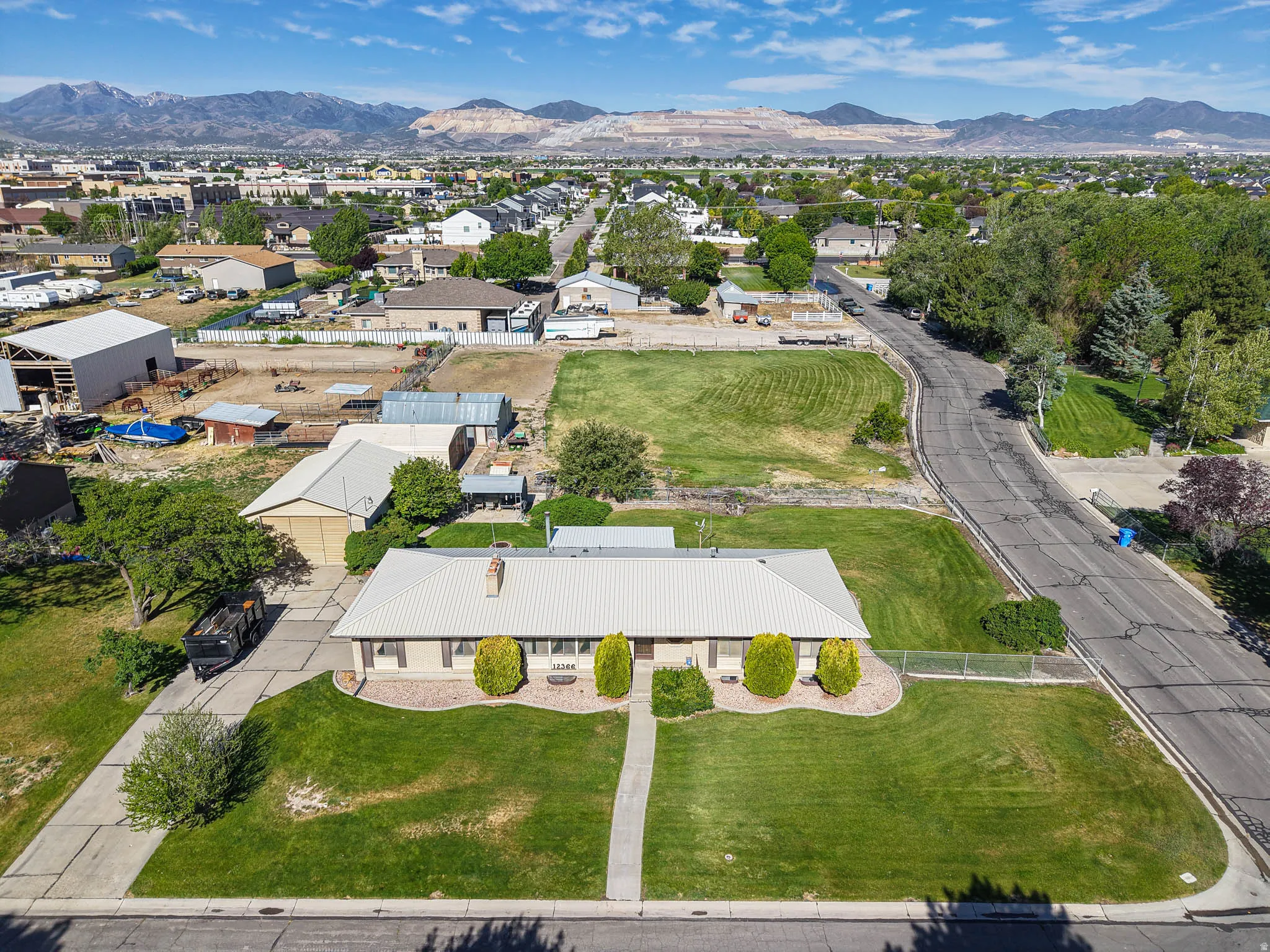 Ranch-style residence featuring a metal roof, a manicured front lawn, and a concrete driveway