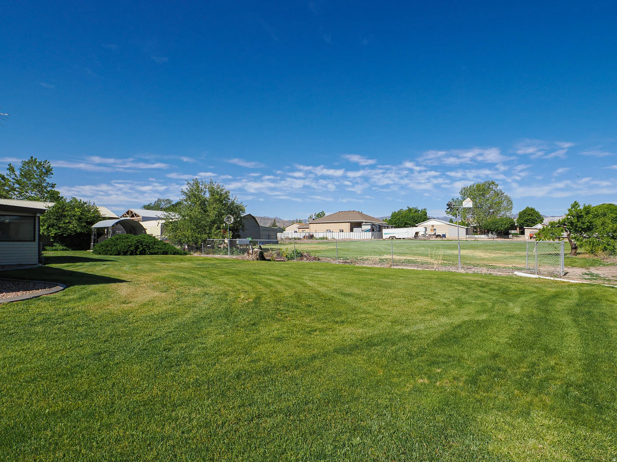 Expansive outdoor space featuring a large grassy lawn and a wire fence