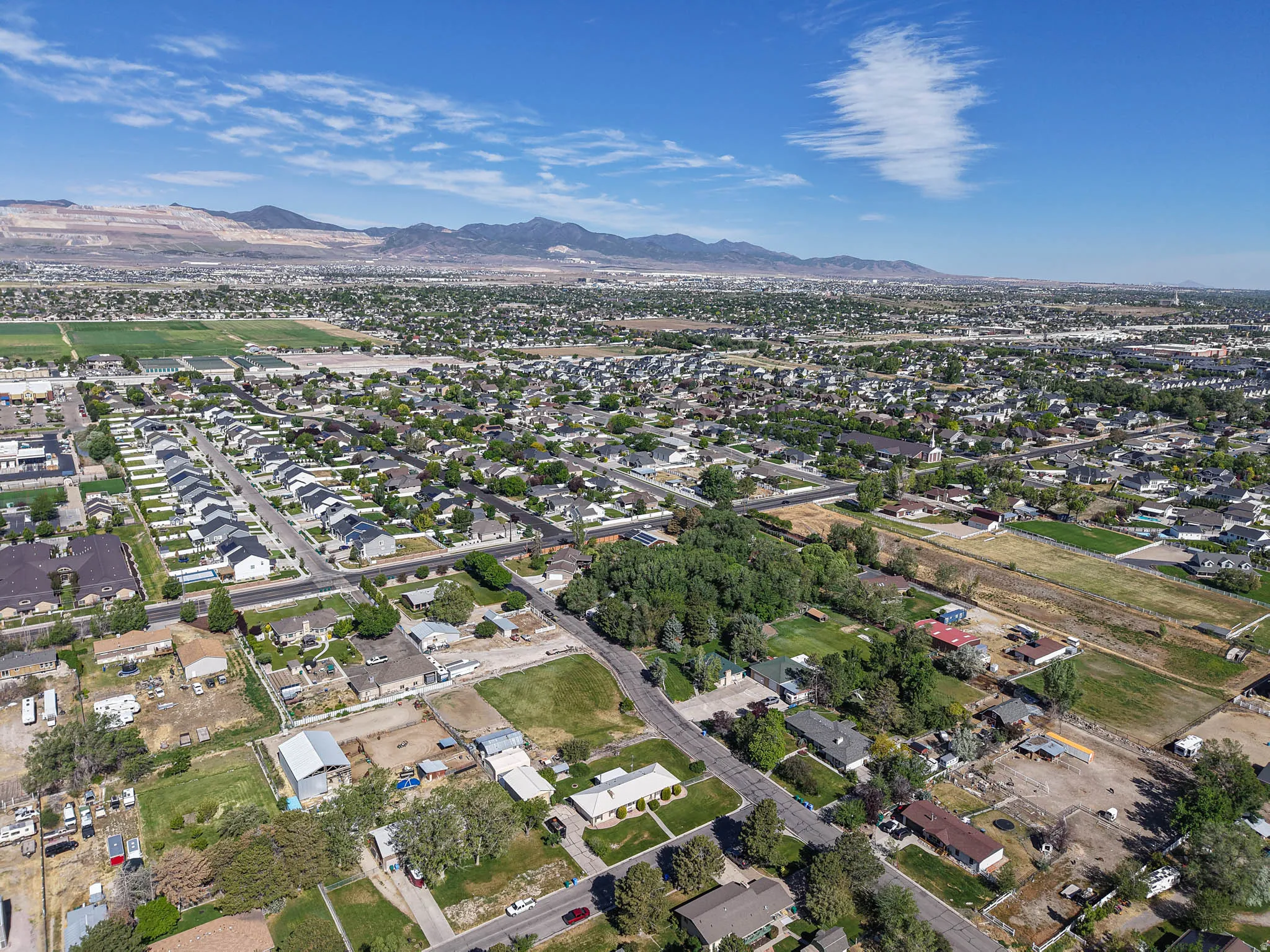 Expansive aerial perspective showcasing a residential area with diverse property types, framed by distant mountains and a clear sky