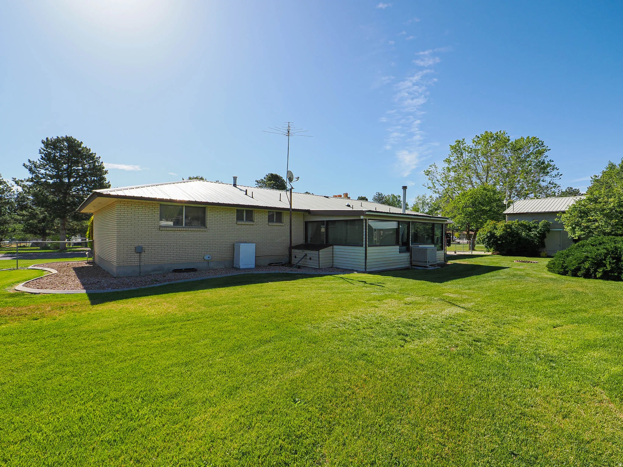 Expansive green lawn bordering a brick exterior residence with a screened-in porch