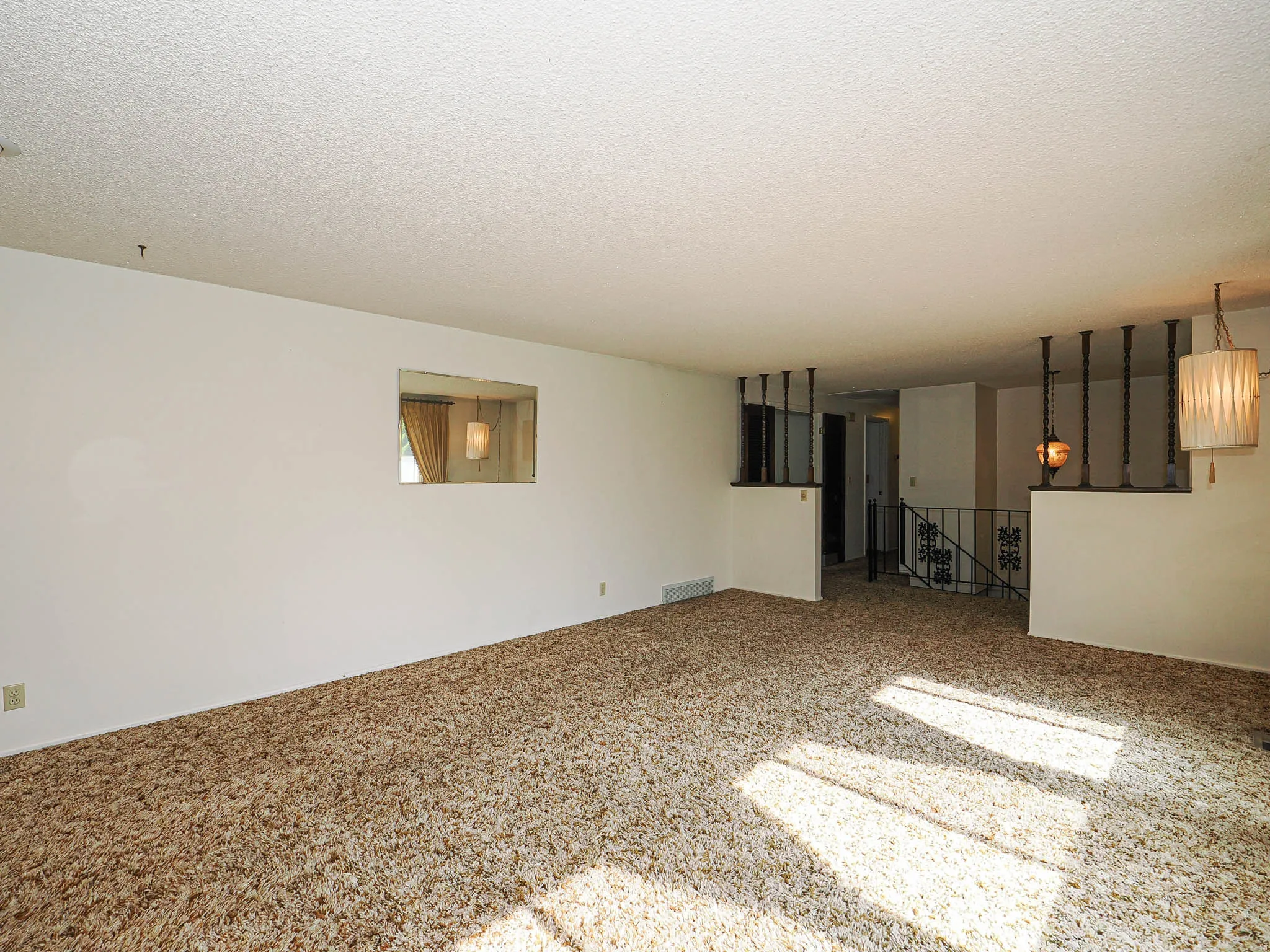 Spacious living area featuring textured carpeting, white walls, and a popcorn ceiling