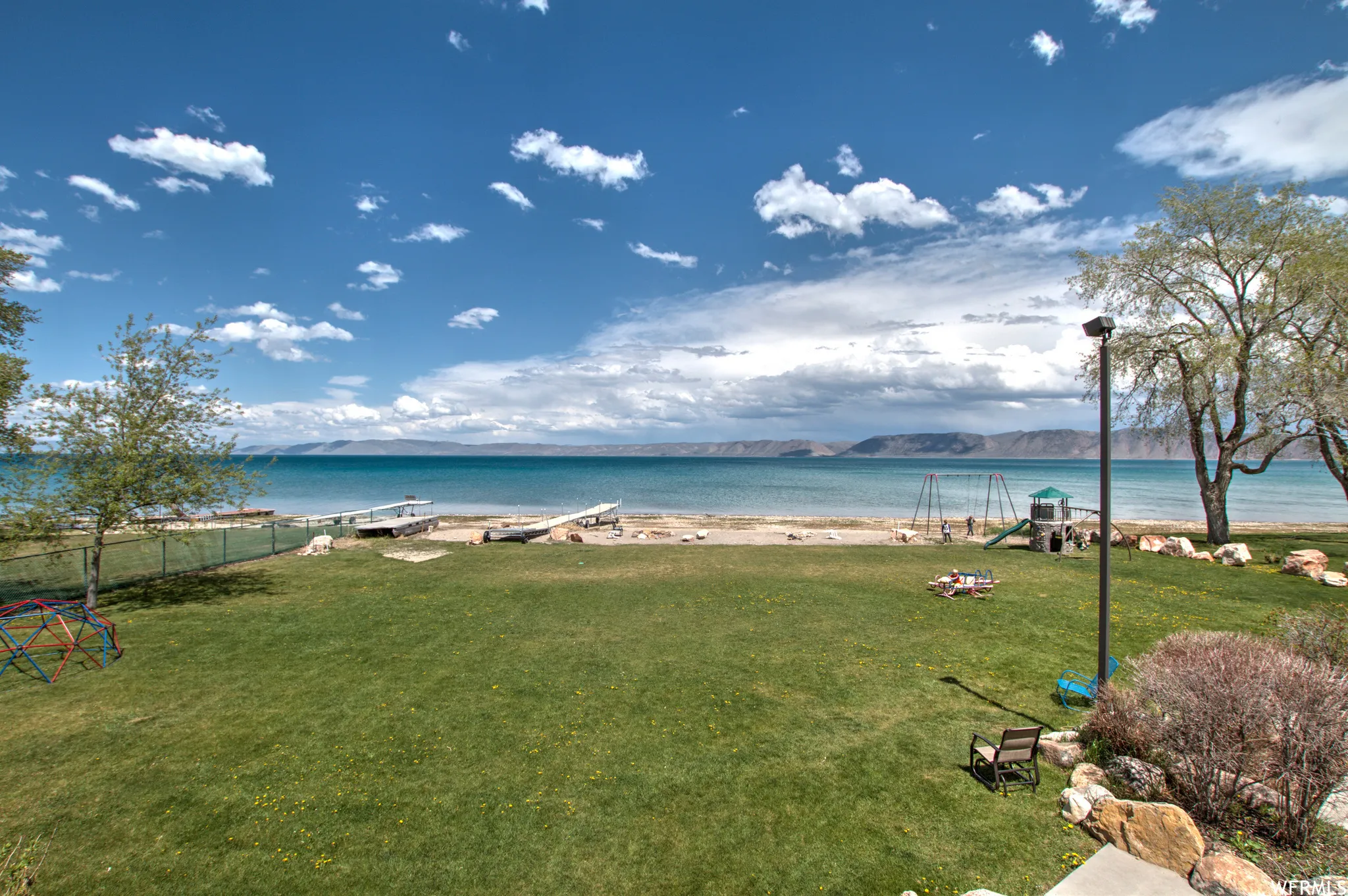 Expansive green lawn extending to a sandy shoreline with direct water access