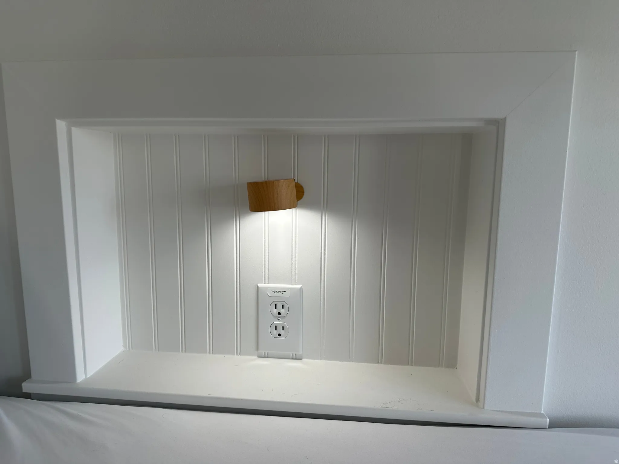 Built-in wall niche with beadboard backing, integrated lighting, and a power outlet