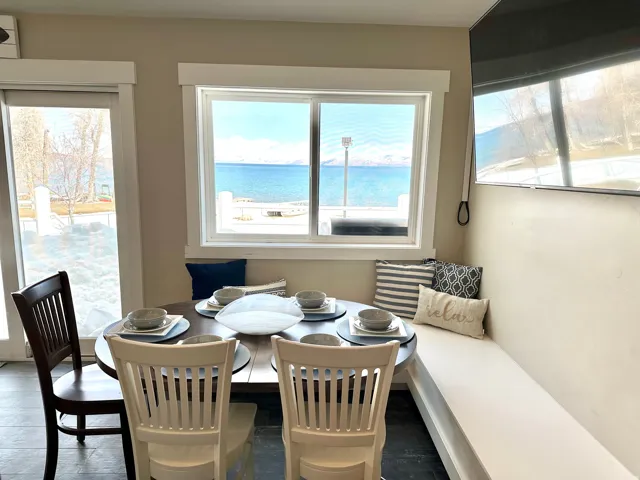 Dining nook featuring a built-in bench, dark tile flooring, and a large window overlooking a body of water with distant mountains