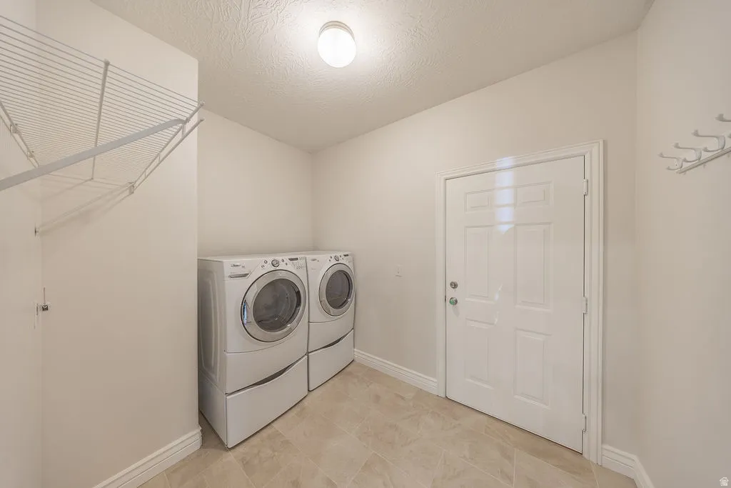 Laundry room featuring tile flooring, a white paneled door, baseboard trim, and a built-in wire shelving system