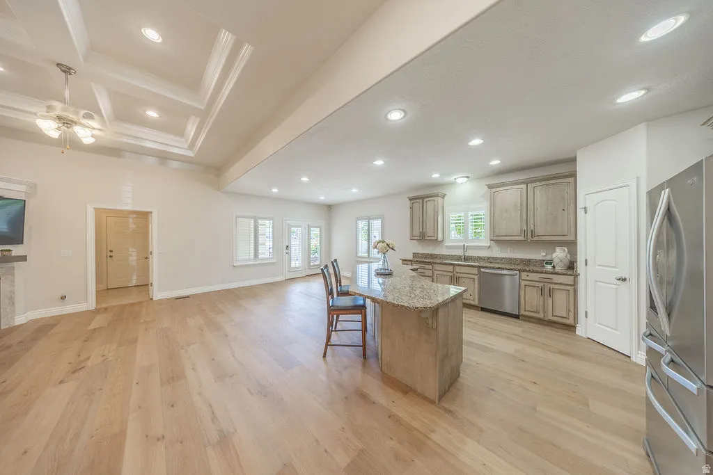 Open-concept living space featuring wood-finish flooring, a tray ceiling with recessed lighting, and a kitchen island with seating