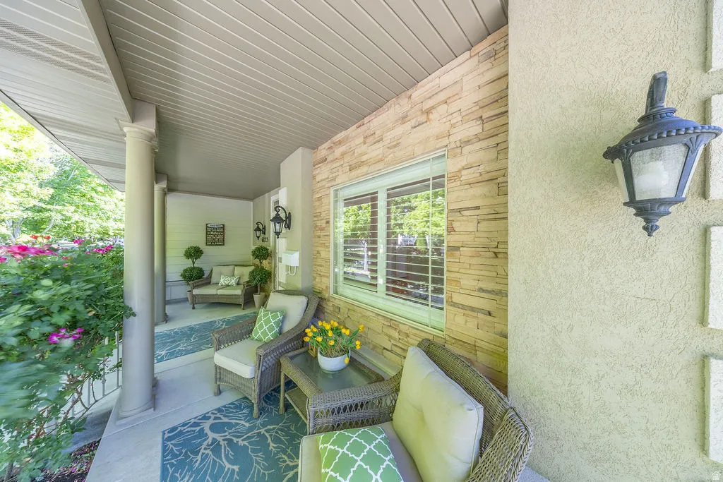 Covered porch with stone accent wall, stucco siding, and decorative exterior lighting