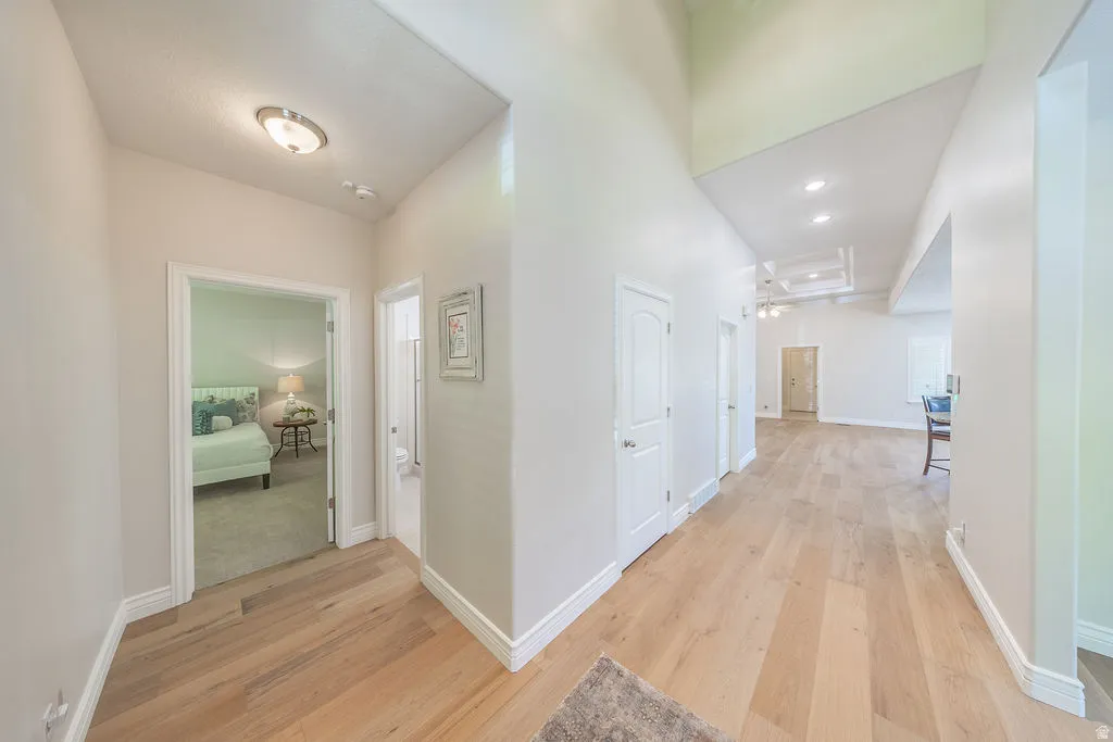 Spacious hallway featuring light wood-finish flooring, white baseboards, and neutral wall tones
