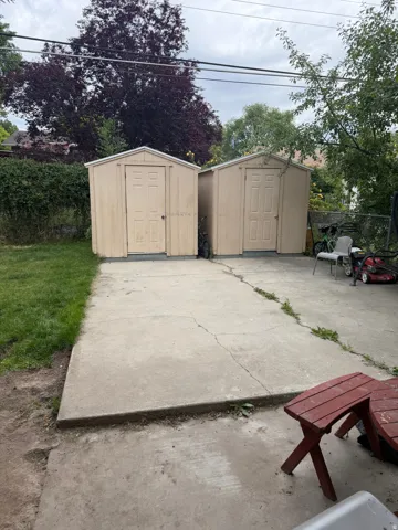 Two outdoor storage sheds featuring beige paneling and gabled roofs