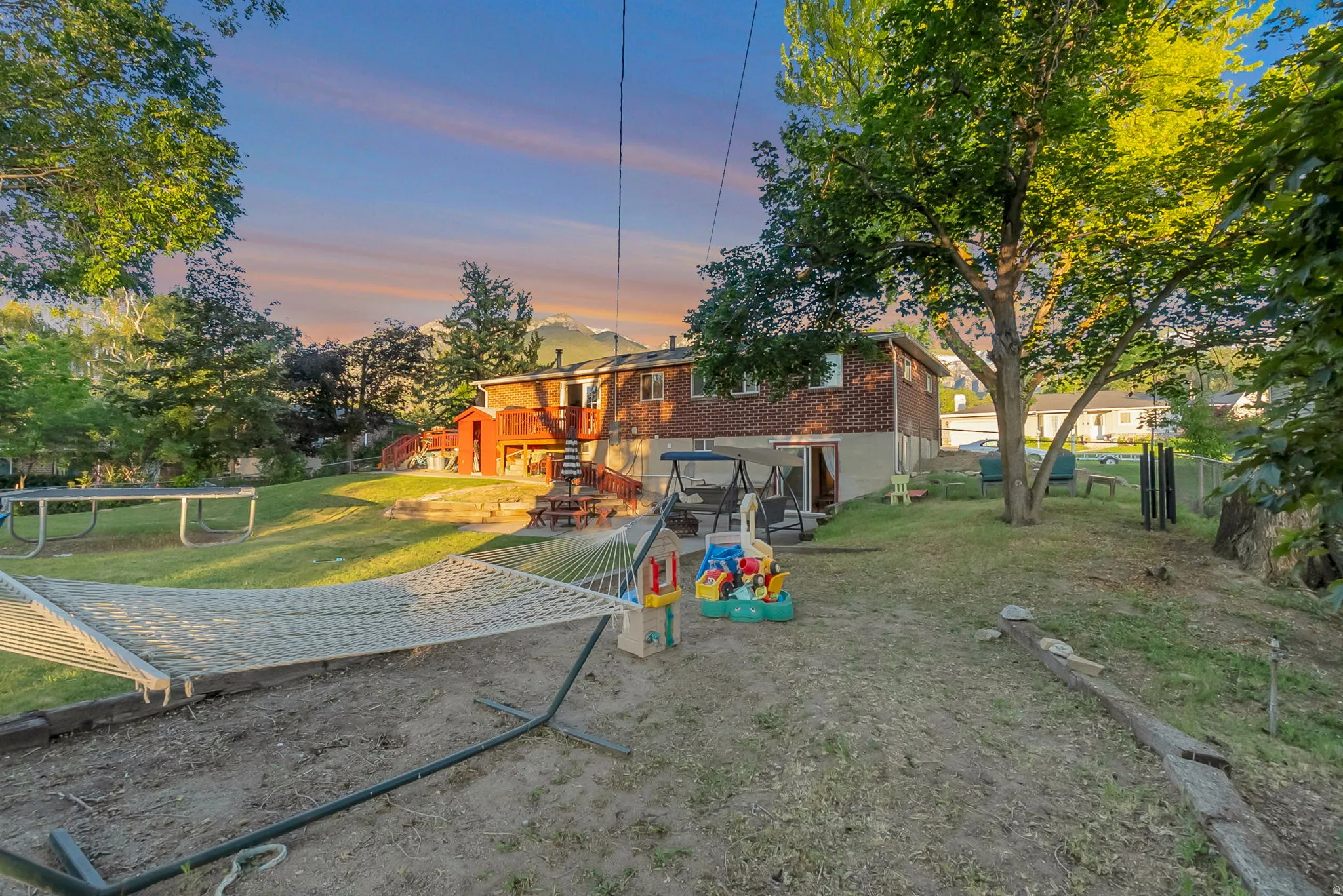 Expansive backyard featuring mature trees, a multi-level deck, and mountain backdrop