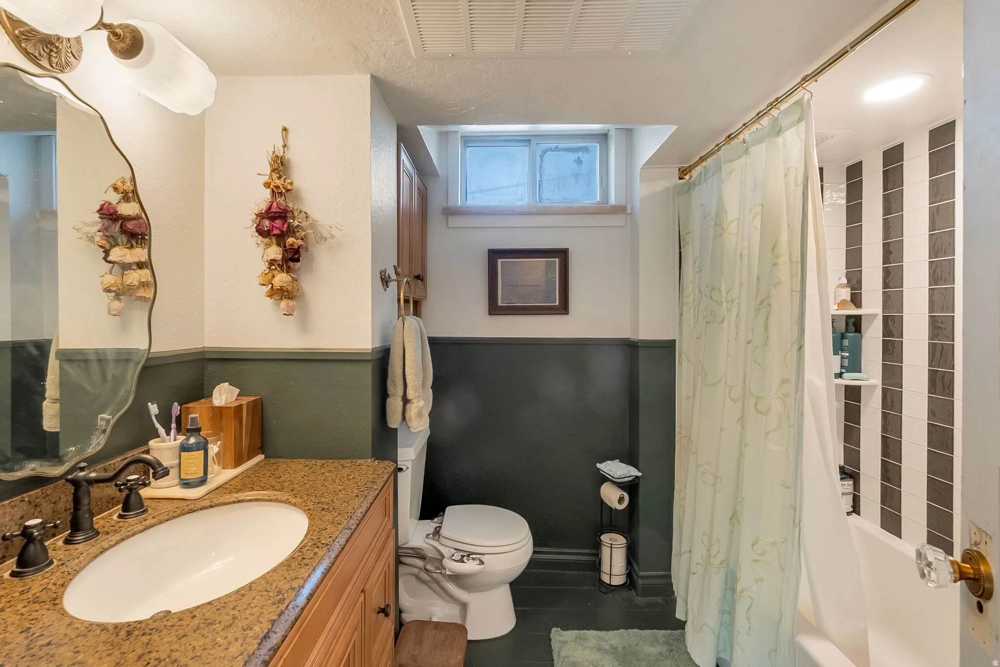 Bathroom featuring a single-sink vanity with a granite countertop, wood-finish cabinetry, and an undermount porcelain sink with an oil-rubbed bronze faucet