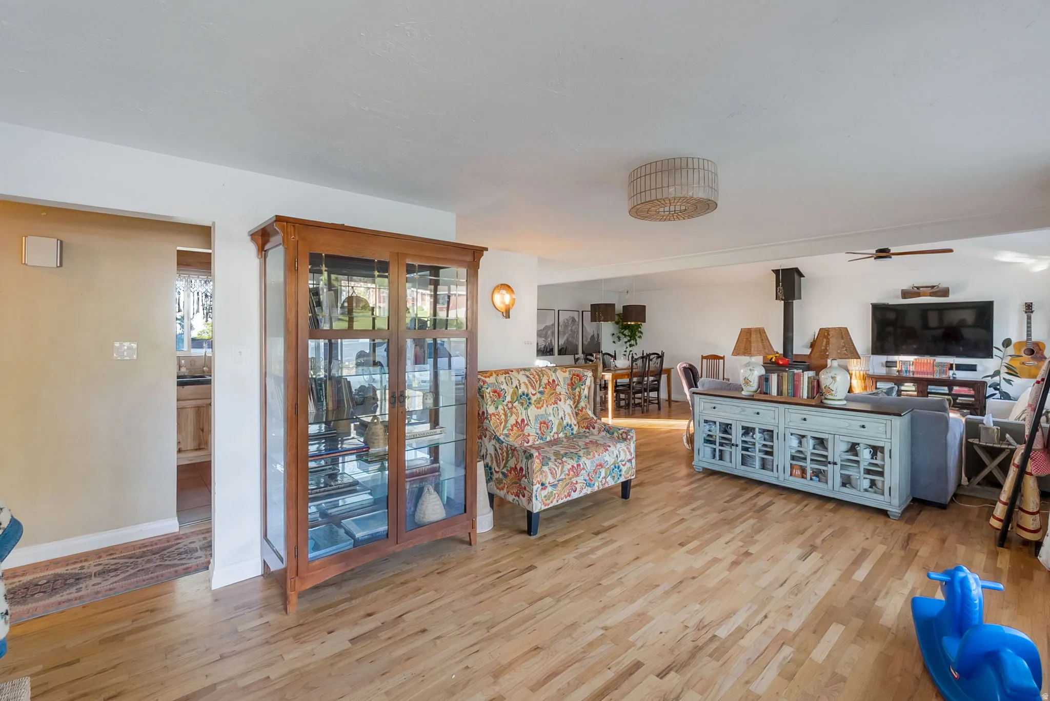 Expansive living area featuring light wood-finish flooring, white walls, and a modern ceiling fan