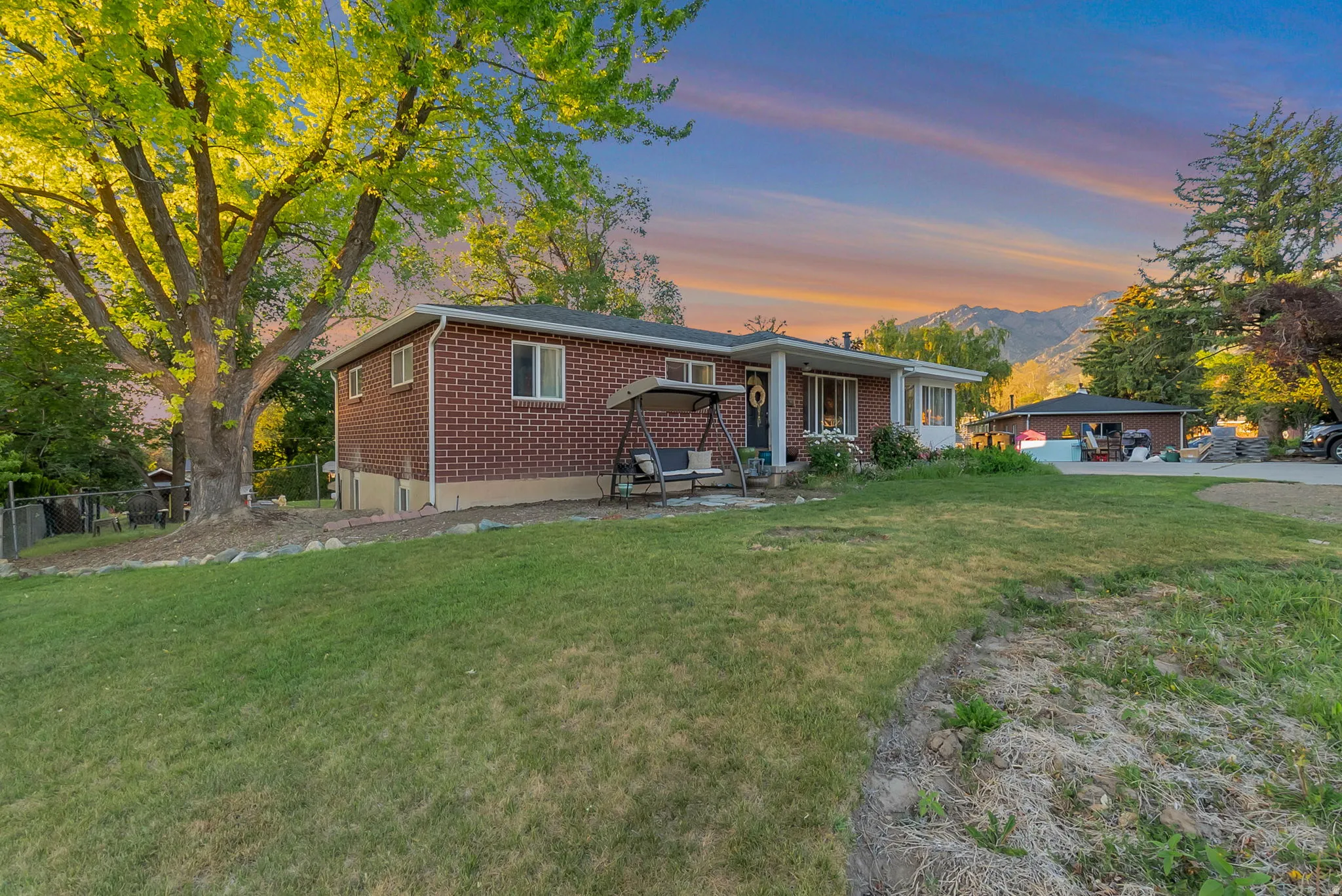 Brick exterior residence with a covered porch and mature trees