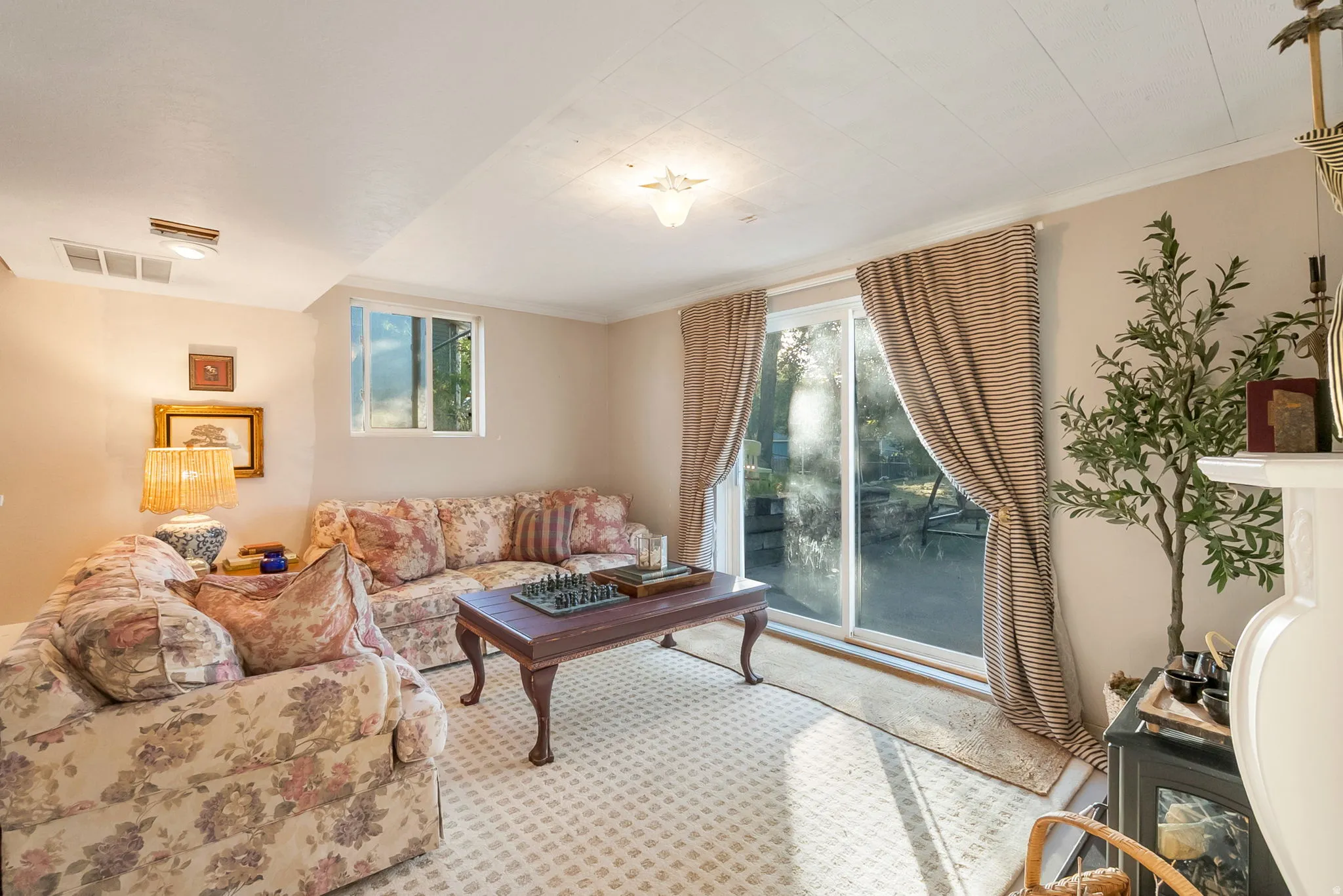 Carpeted living area featuring a sliding glass door, a single window, and a white ceiling with recessed lighting