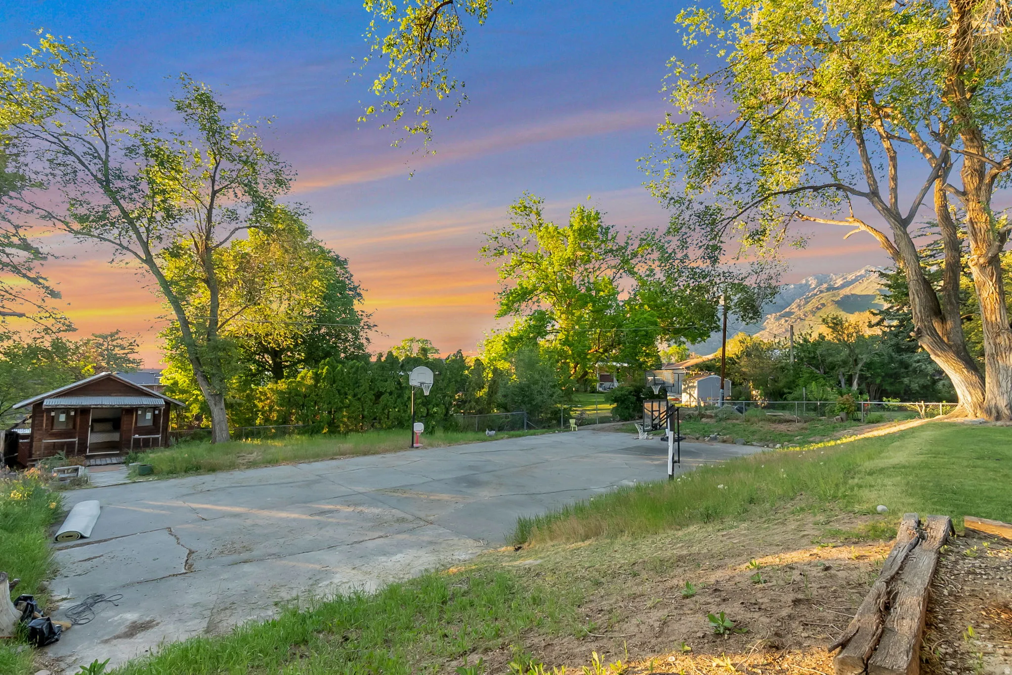 Expansive outdoor recreation area with mature trees and a paved court