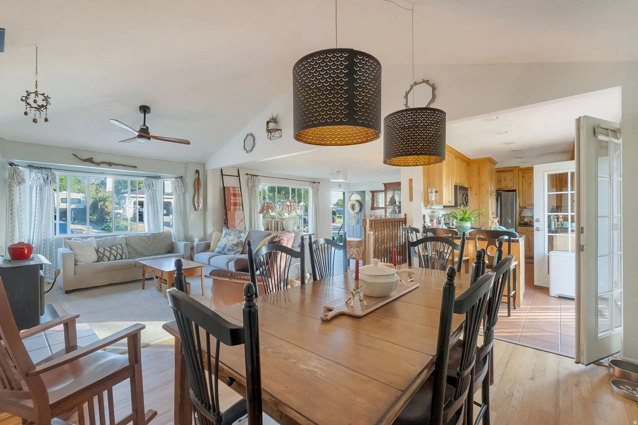 Open-concept dining and living areas featuring wood-finish flooring, vaulted ceilings, and a ceiling fan