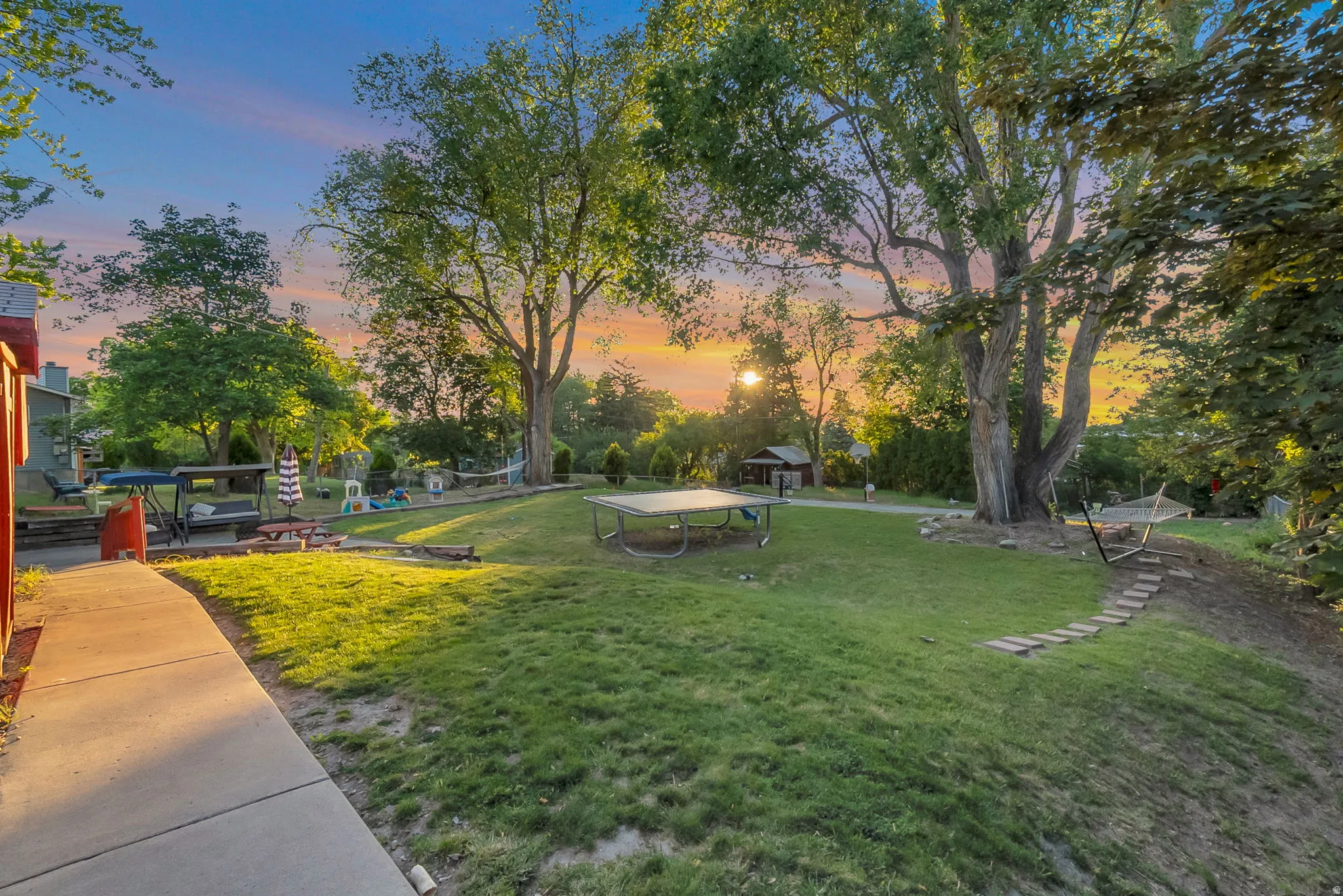 Expansive lawn with mature trees and a concrete pathway