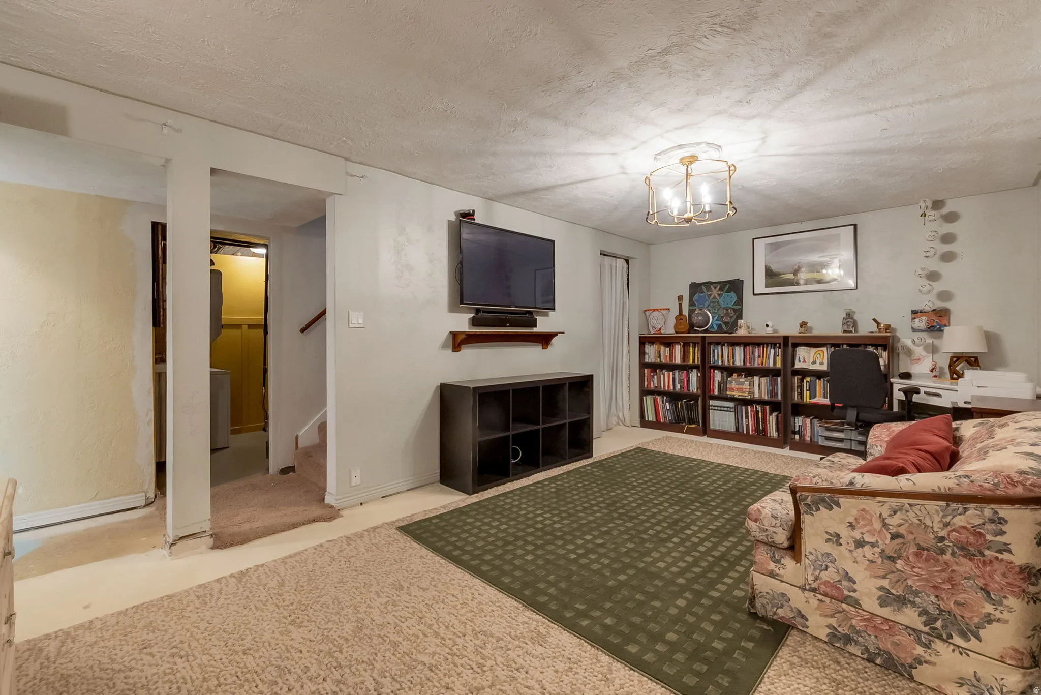 Carpeted room with a ceiling-mounted light fixture, built-in shelving, and a wall-mounted media console