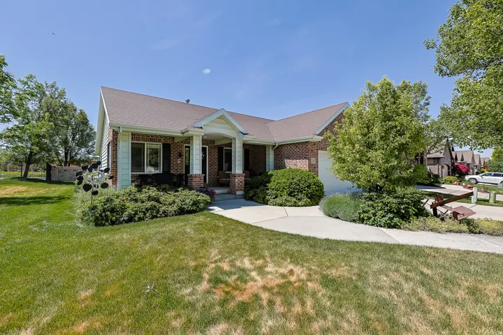Brick and siding exterior featuring a covered entry, attached garage, and mature landscaping