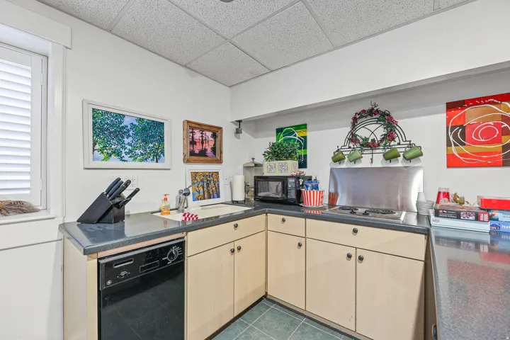Corner kitchen area featuring light wood-finish cabinetry and dark countertops
