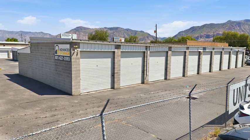 Storage facility featuring multiple units with roll-up doors, concrete block construction, and a paved lot