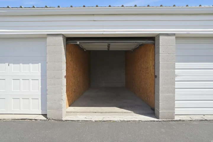 Open garage bay featuring concrete block construction and plywood-lined interior walls