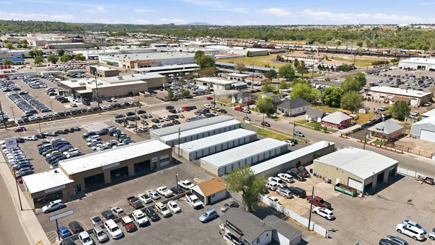 Expansive commercial property featuring multiple buildings with metal roofs, large paved parking areas, and surrounding commercial and residential structures