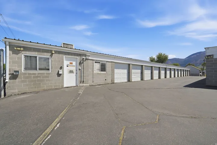Concrete block building with multiple roll-up garage doors, a white entry door, and two windows