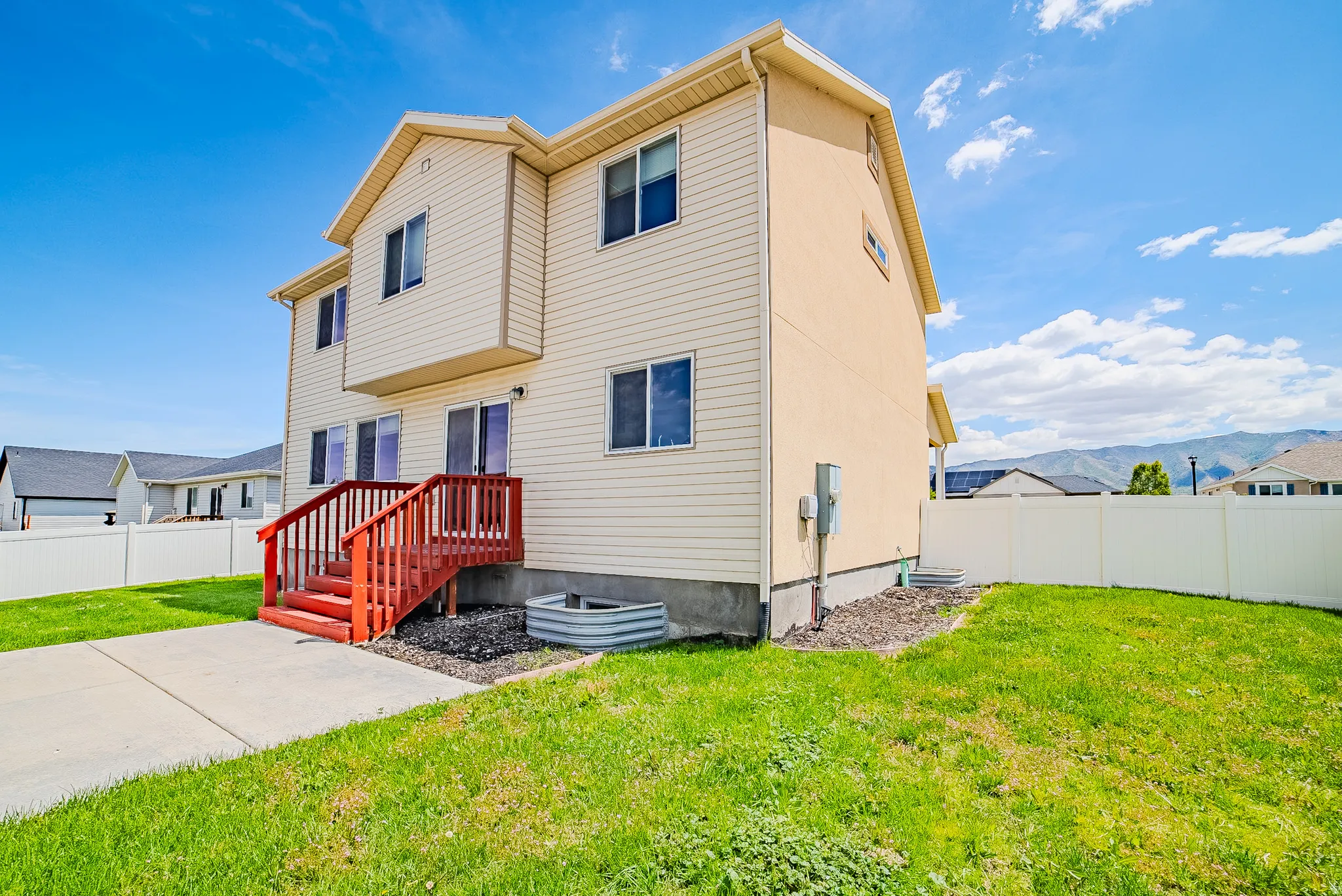 Two-story residential structure featuring beige vinyl siding and a red exterior staircase