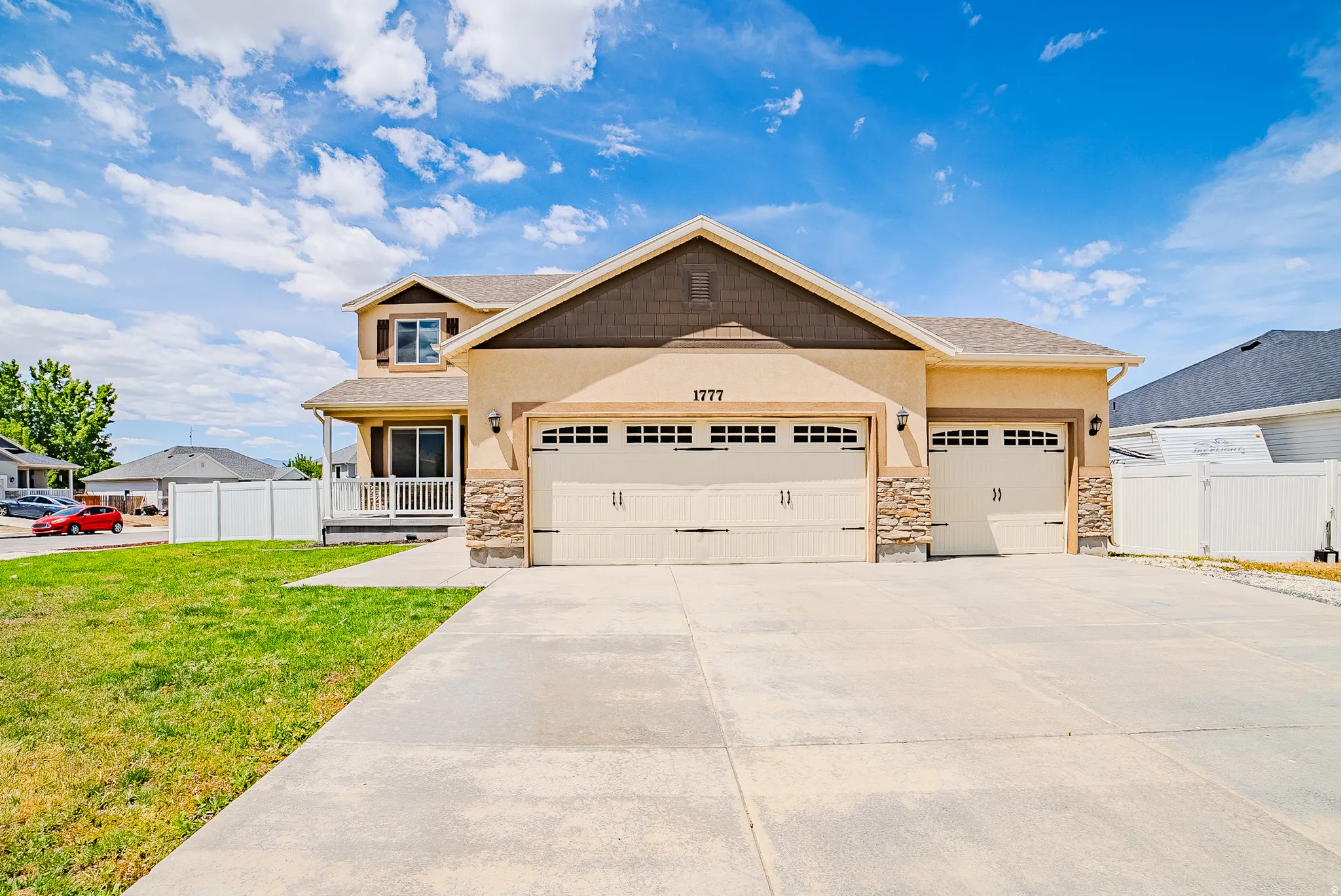 Stucco exterior featuring stone accents, a three-car garage, and a covered porch