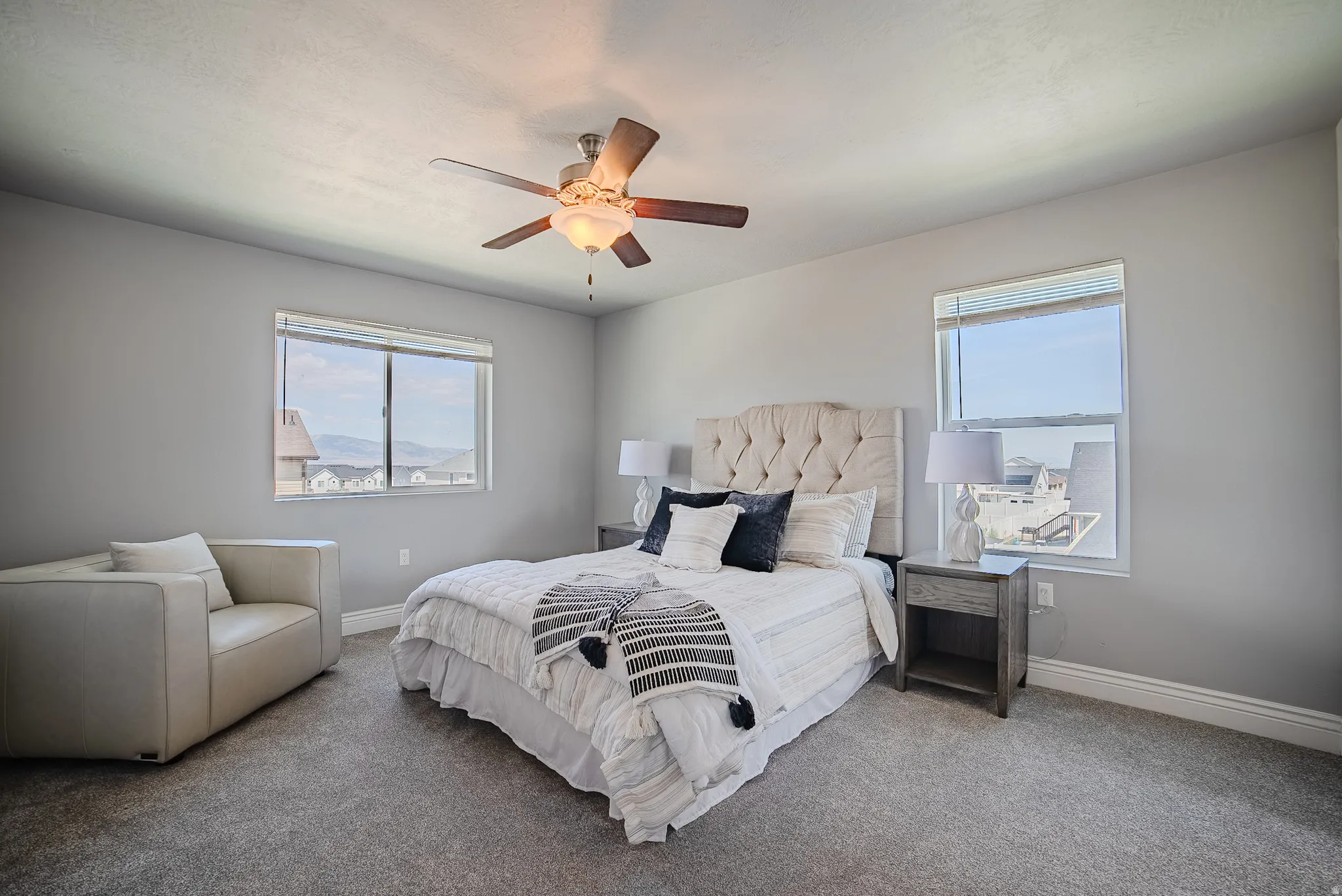Carpeted room featuring multiple windows with blinds, a ceiling fan with integrated lighting, and painted walls with baseboard molding