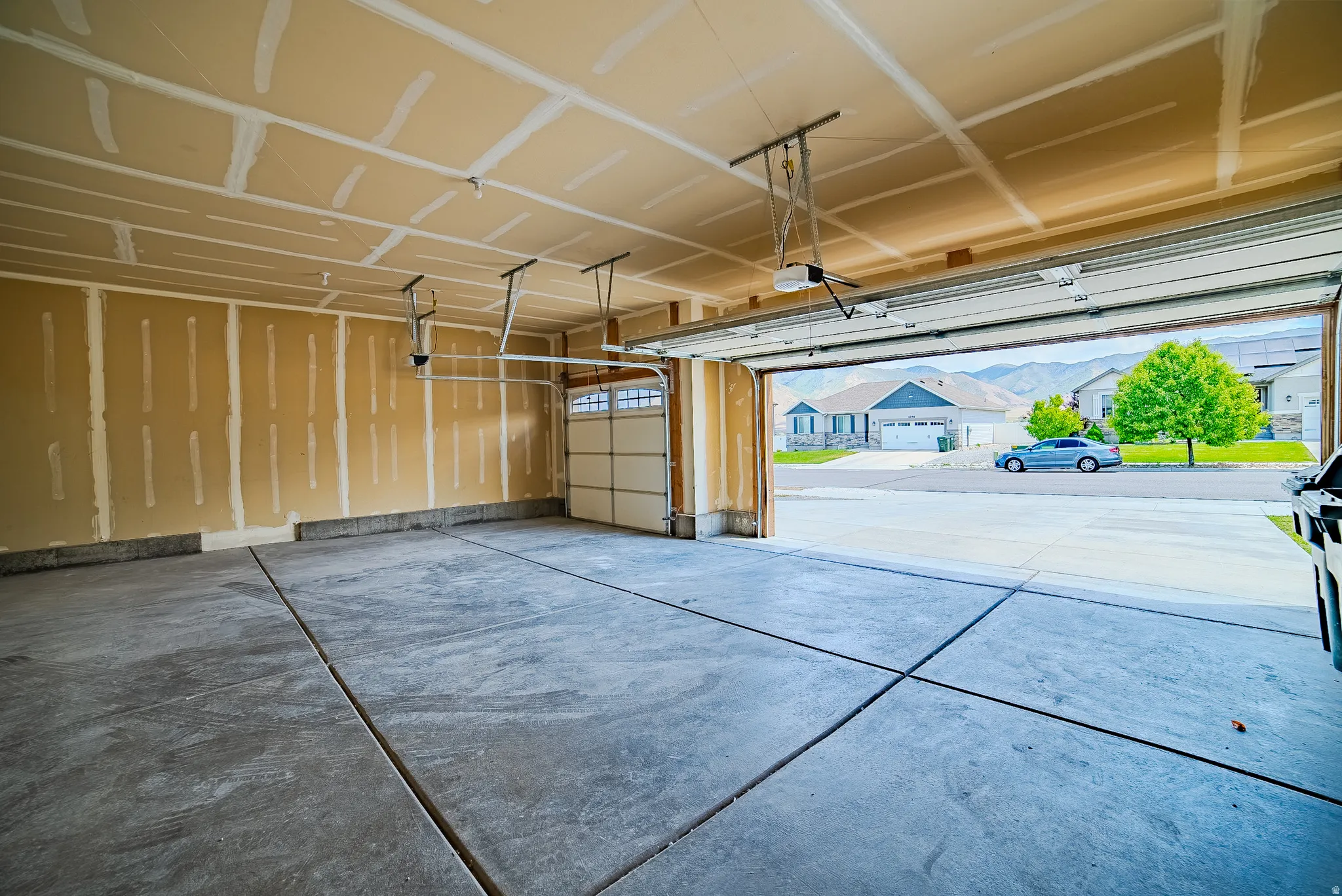 Spacious two-car garage with concrete flooring and exposed drywall