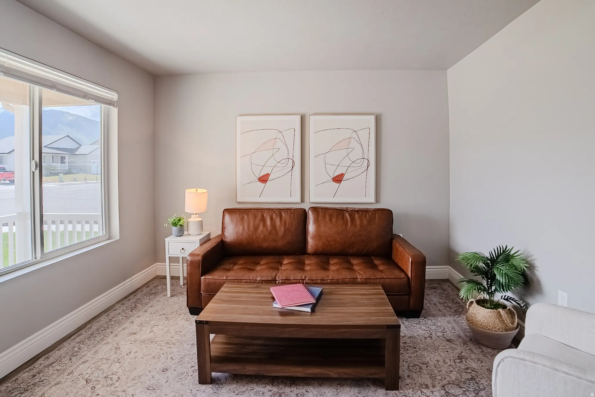 Living area featuring neutral wall tones, large window with ample natural light, and patterned area rug over wood-finish flooring
