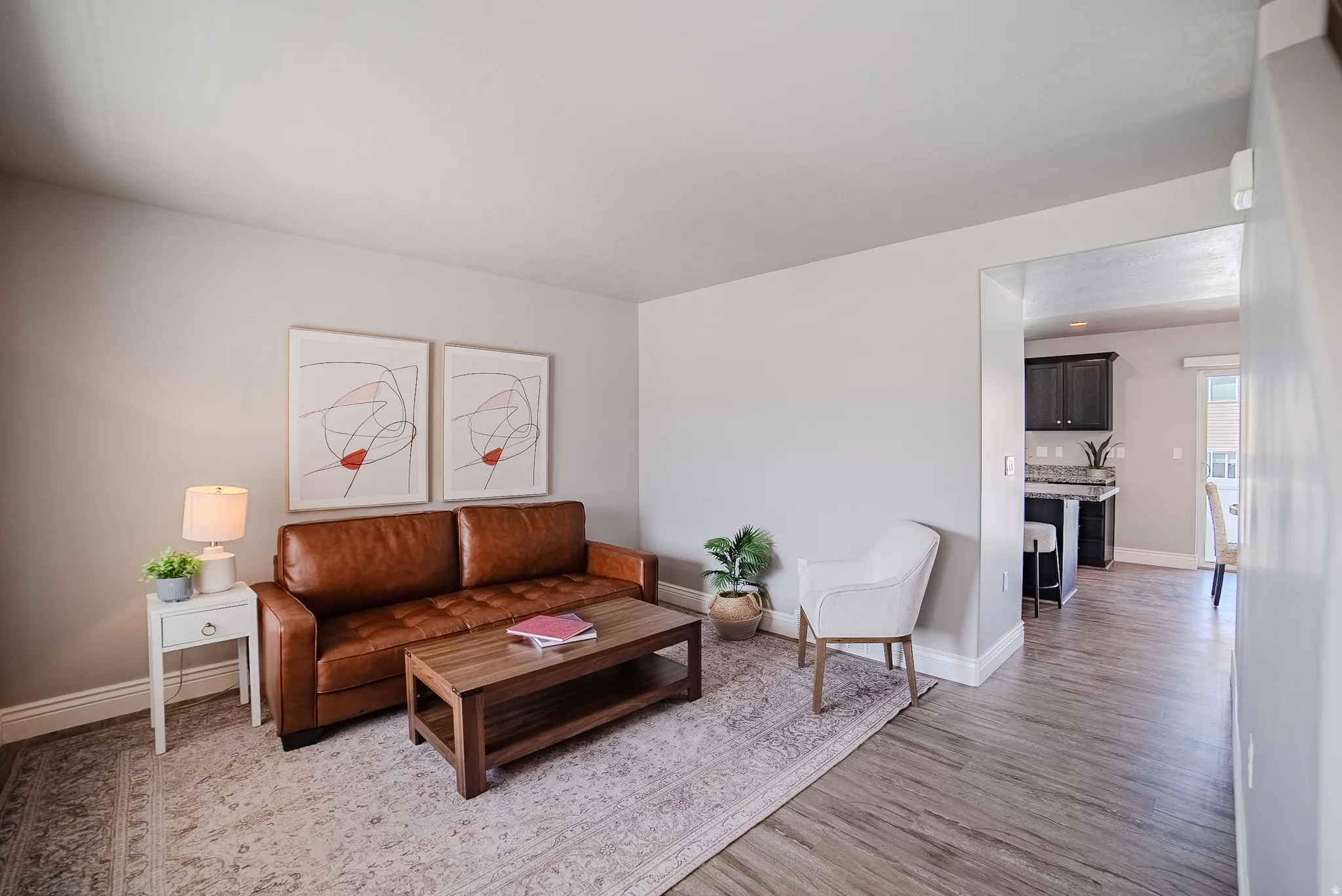 Spacious living area featuring light-toned walls and wood-finish flooring