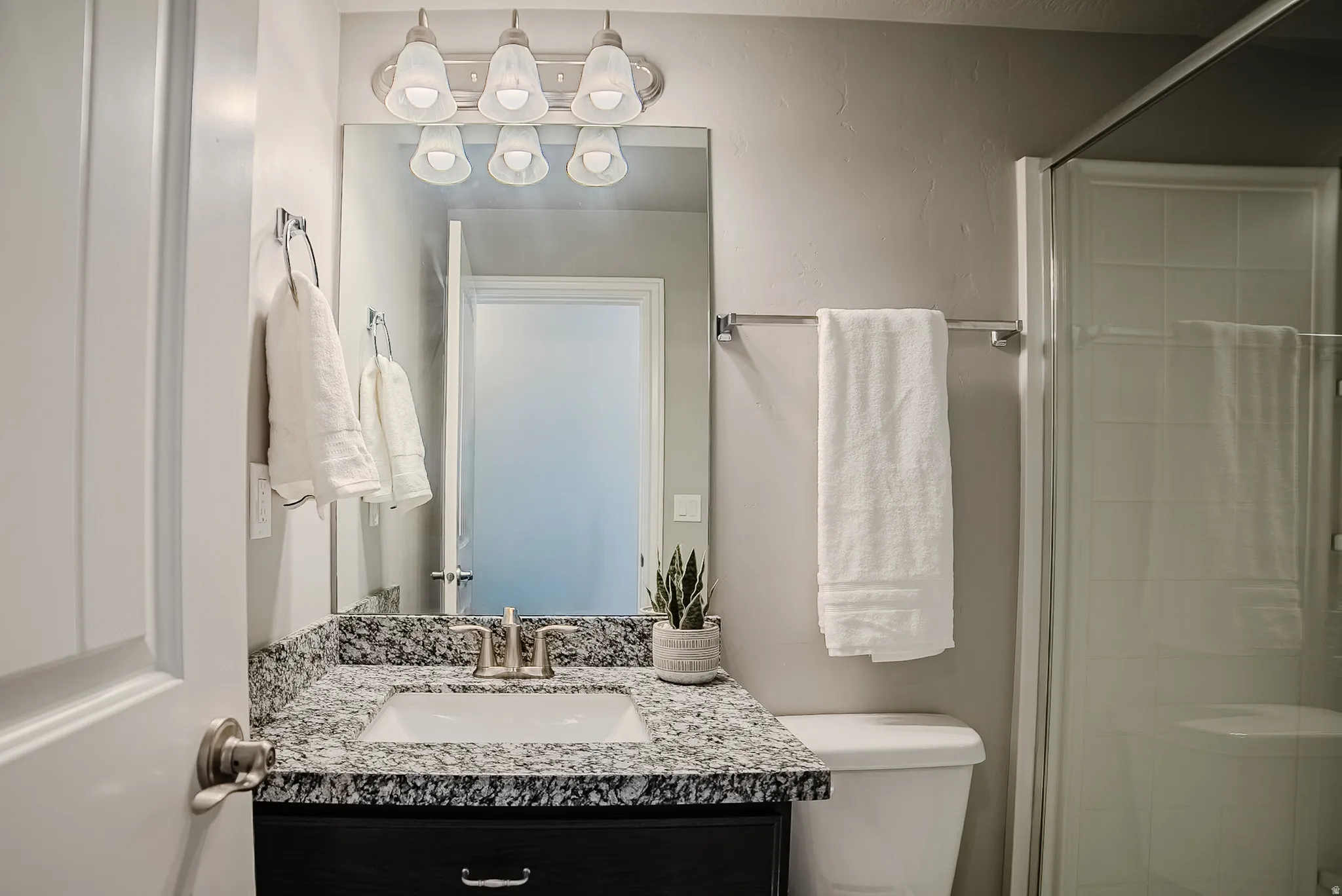 Vanity featuring a rectangular sink, speckled countertop, and a brushed nickel faucet