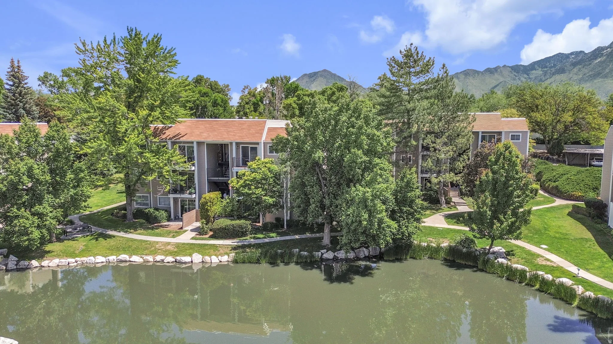 Multi-story residential buildings with brown shingle roofs and light-colored siding, overlooking a body of water