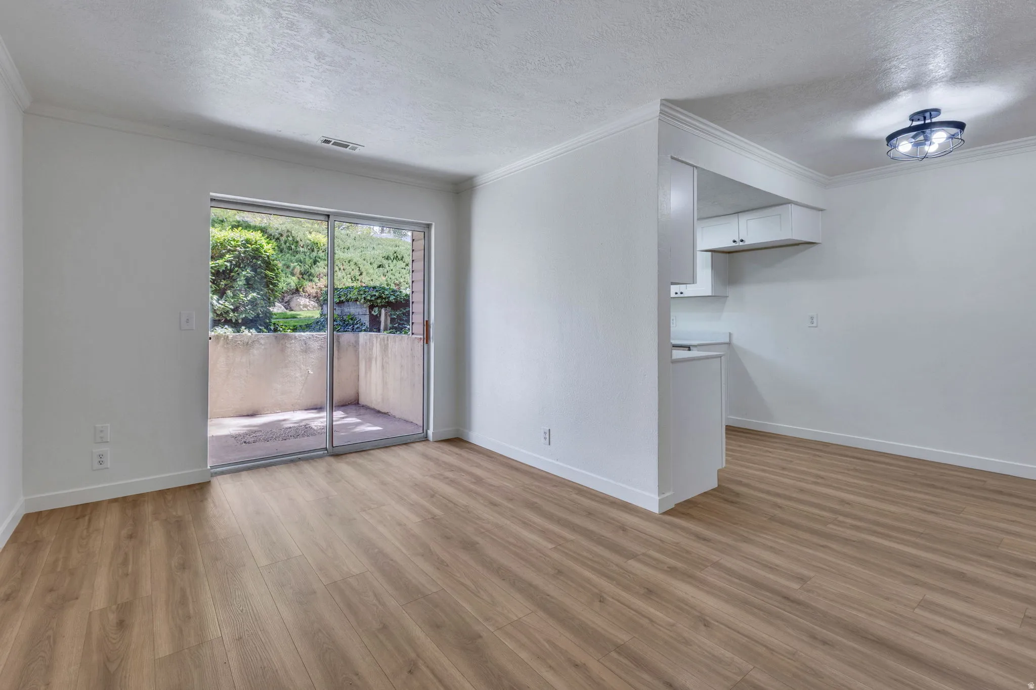 Open concept living space featuring wood-finish flooring, white walls, and crown molding