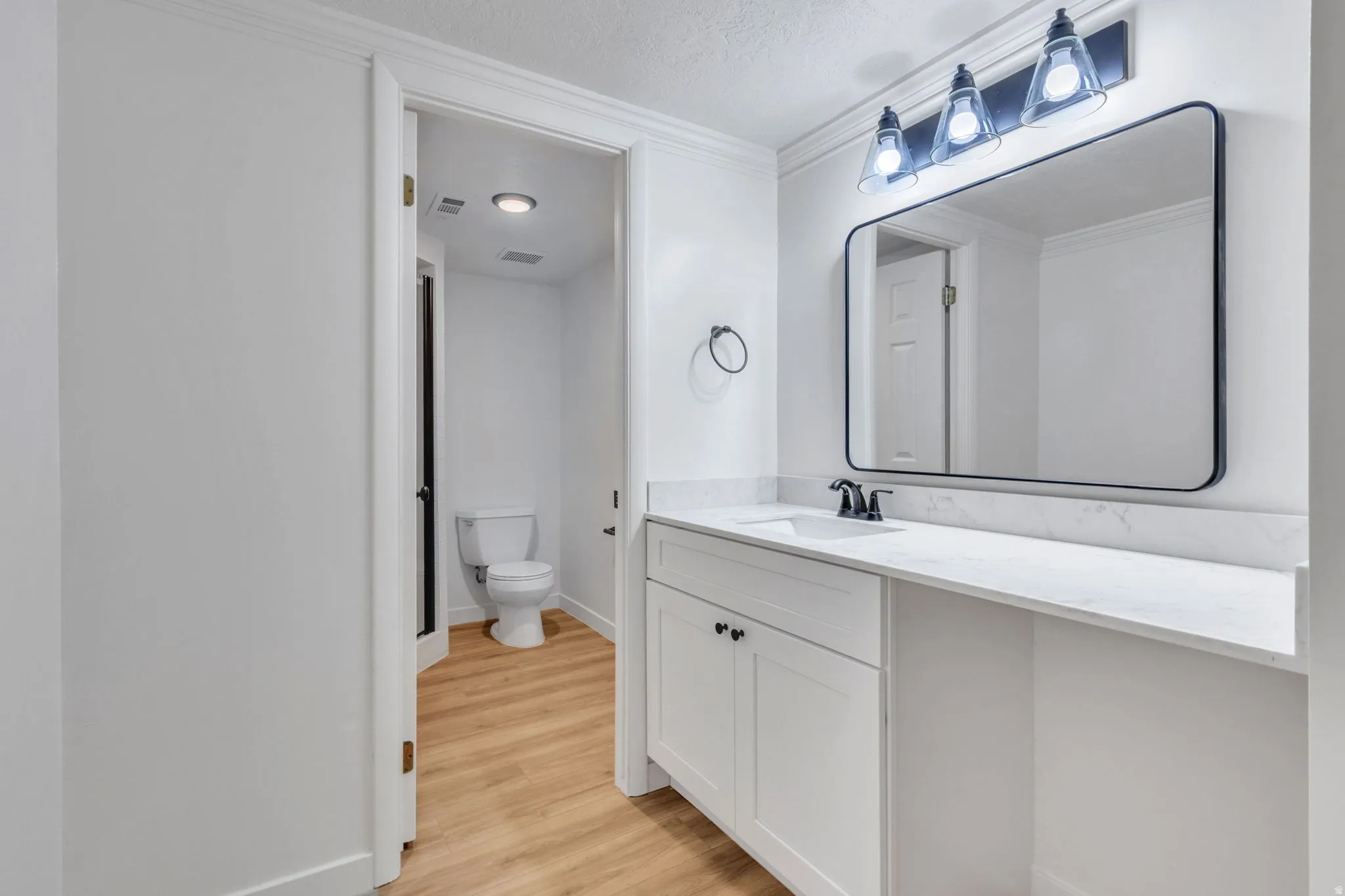 Bathroom vanity with white cabinetry, a white countertop, and a rectangular mirror with a matte black frame