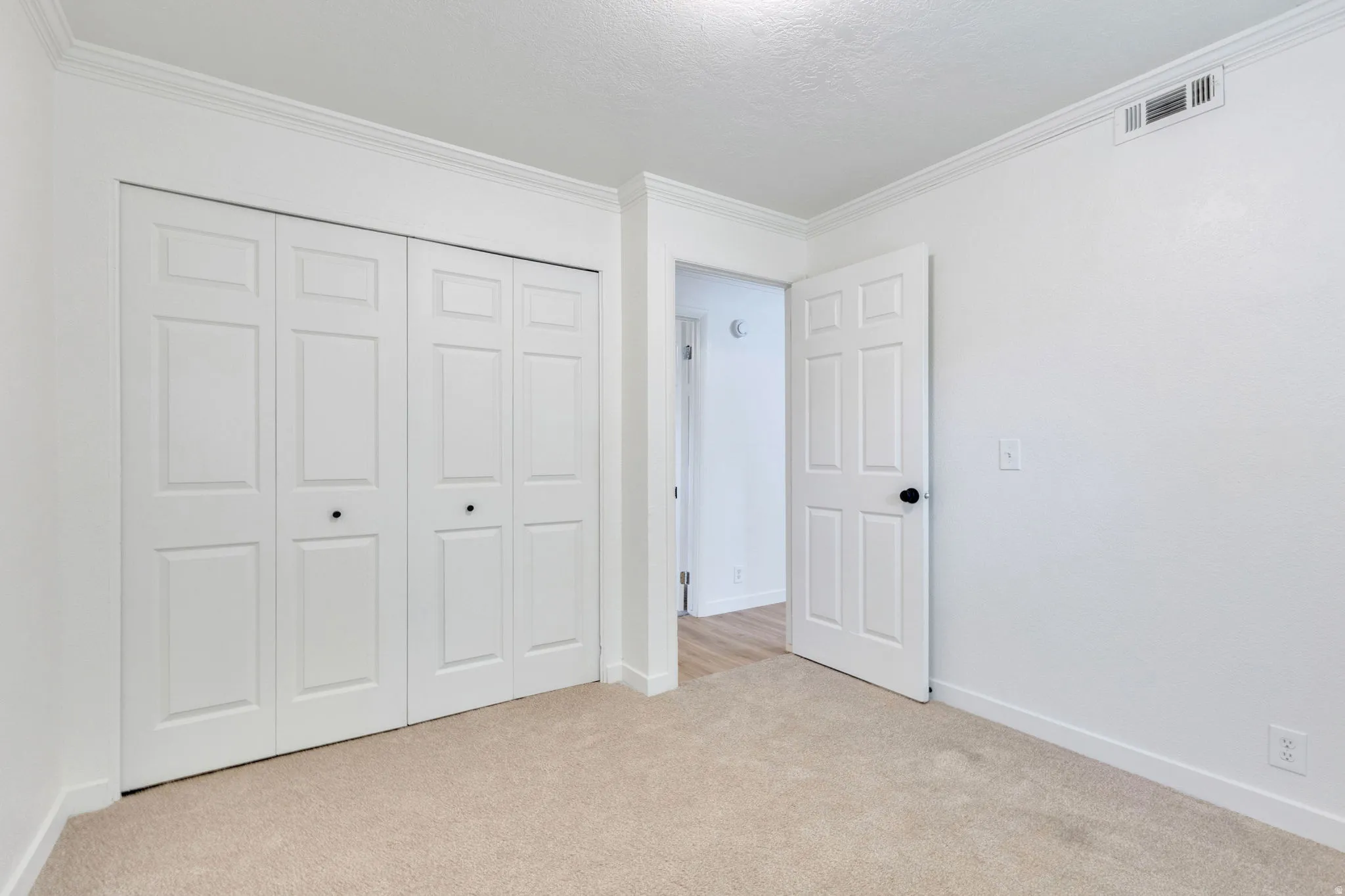 Bedroom featuring neutral-toned carpet, white walls, and crown molding