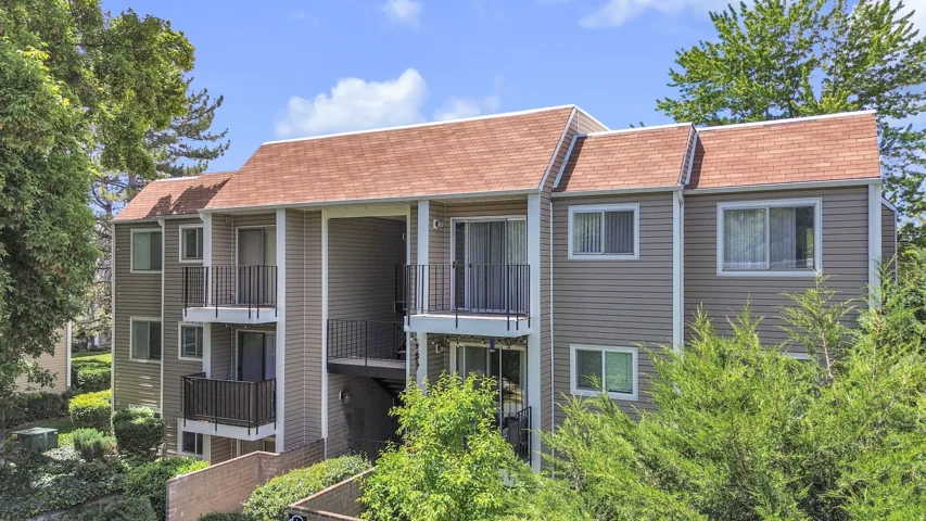Multi-level building with tan siding and a reddish-brown shingle roof