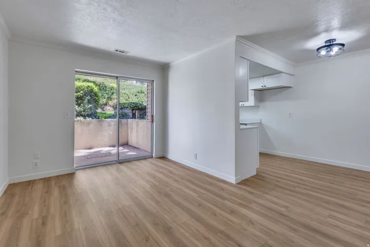 Open concept living space featuring wood-finish flooring, white walls, and crown molding
